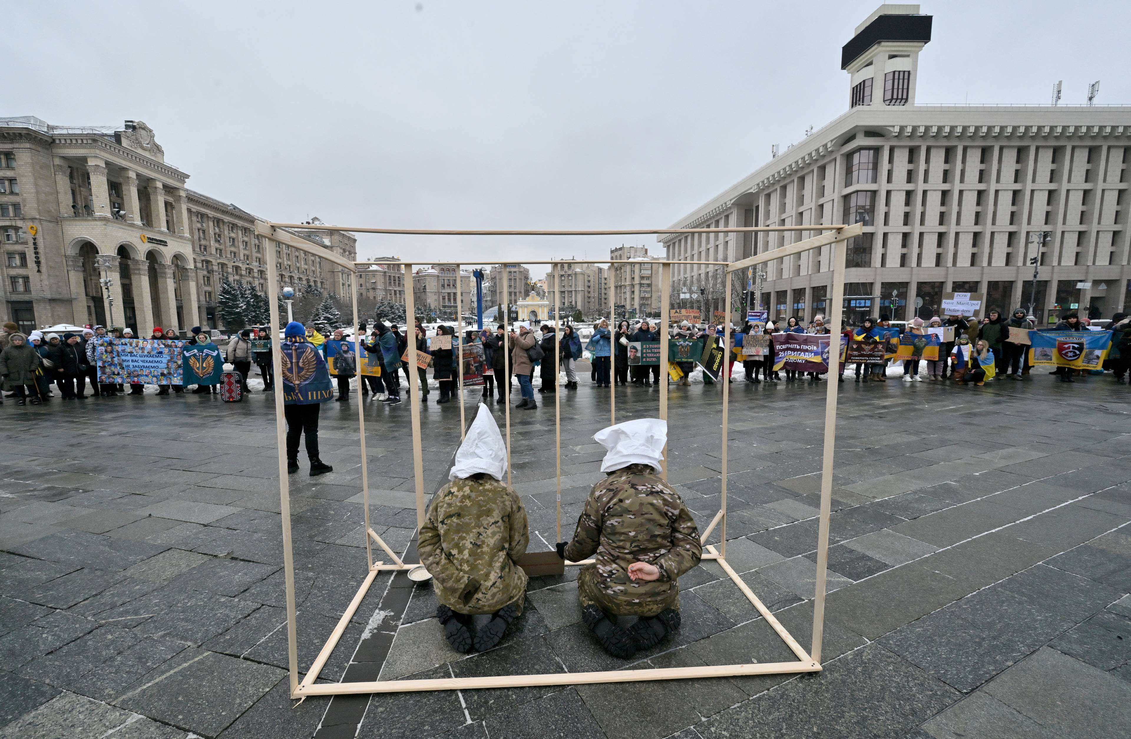 Dwie osoby w białych kaptórach w klatce ustawionej na placu w centrum Kijowa