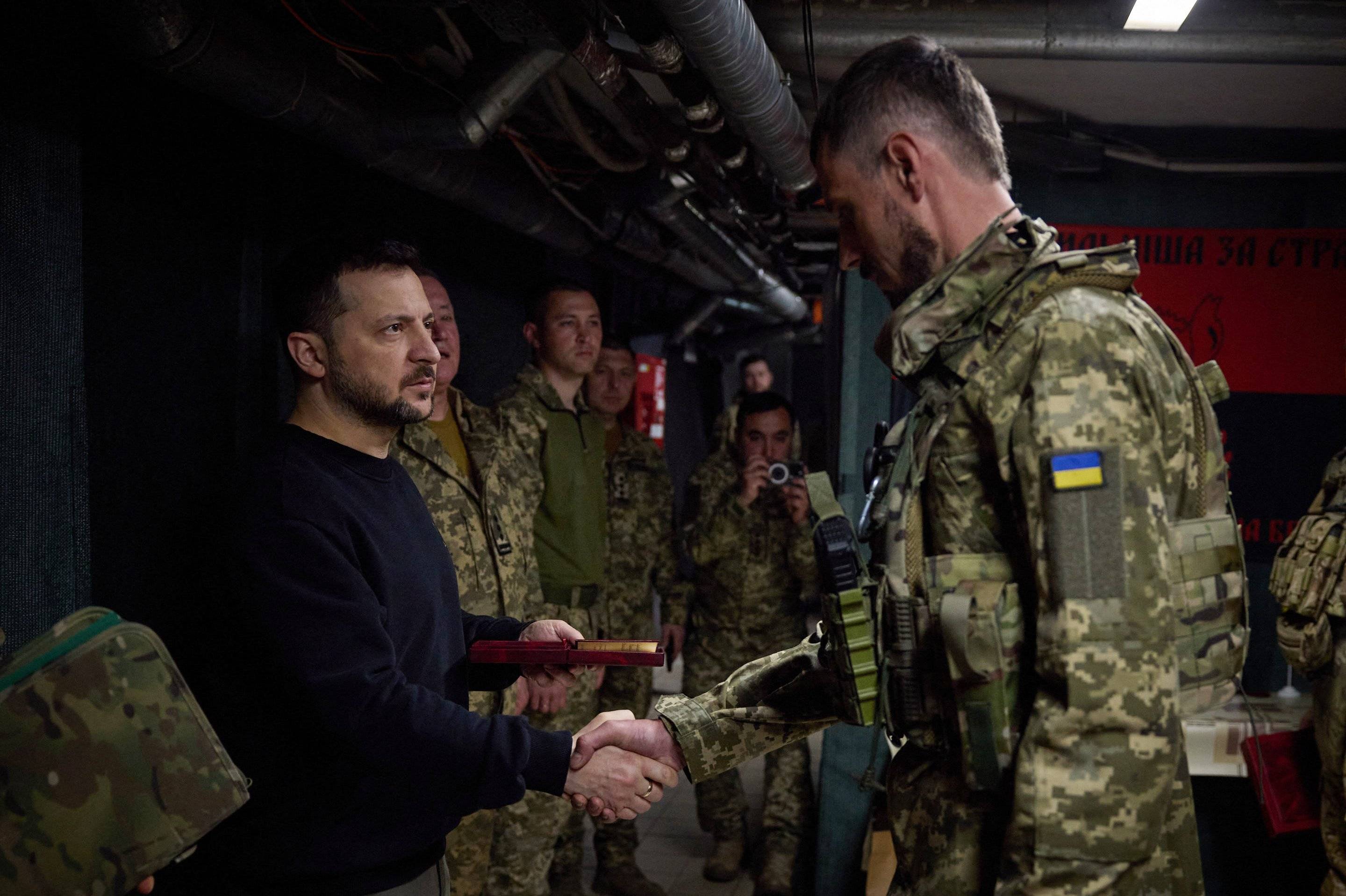Mężczyzna w ciemnym stroju ściska rękę żołnoierzowi ukraińskiemu