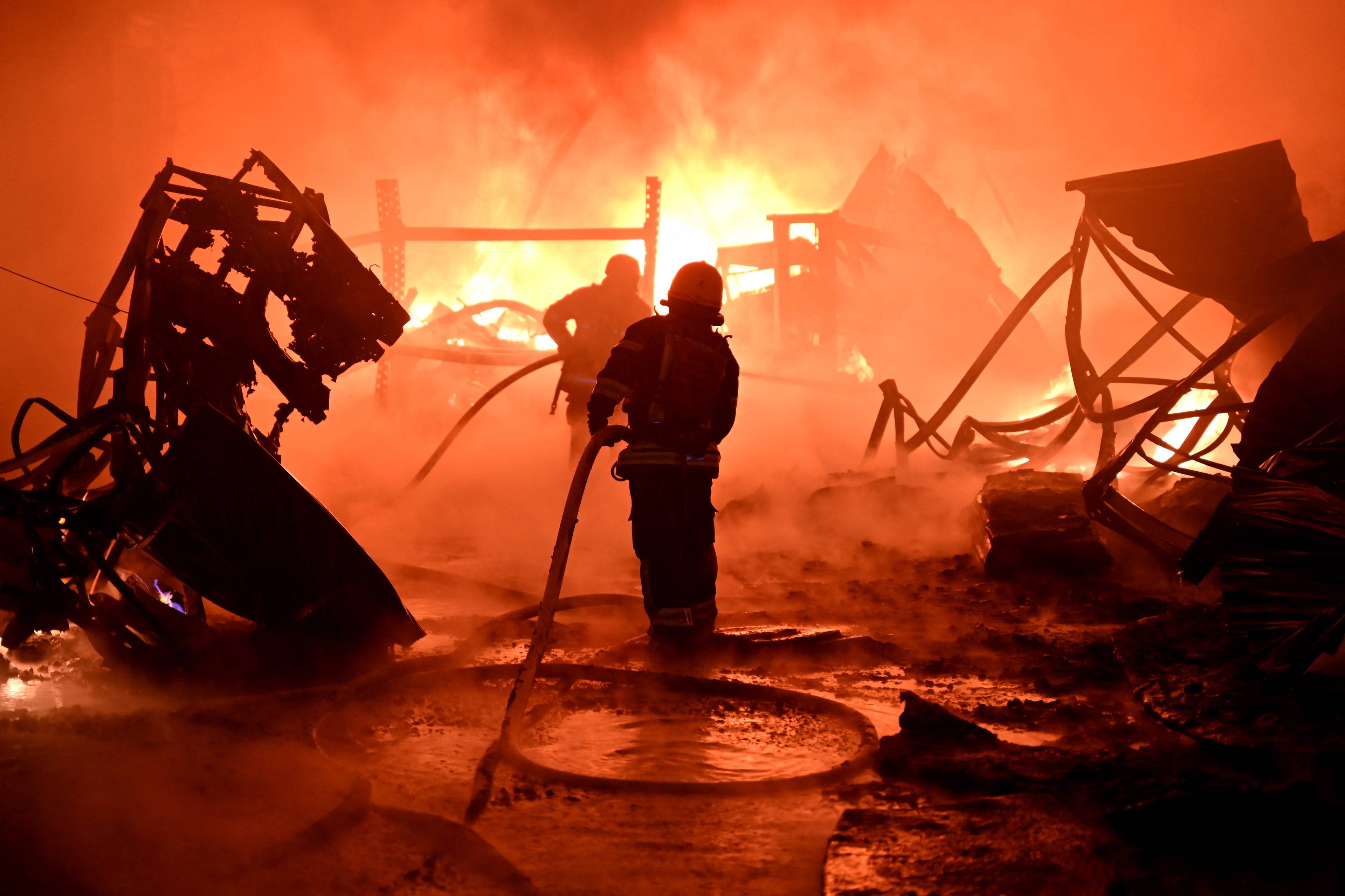 Na zdjęciu znajdują się dwaj strażacy, którzy gaszą pożar po rosyjskim ataku na Charków. Są w środku ognia.