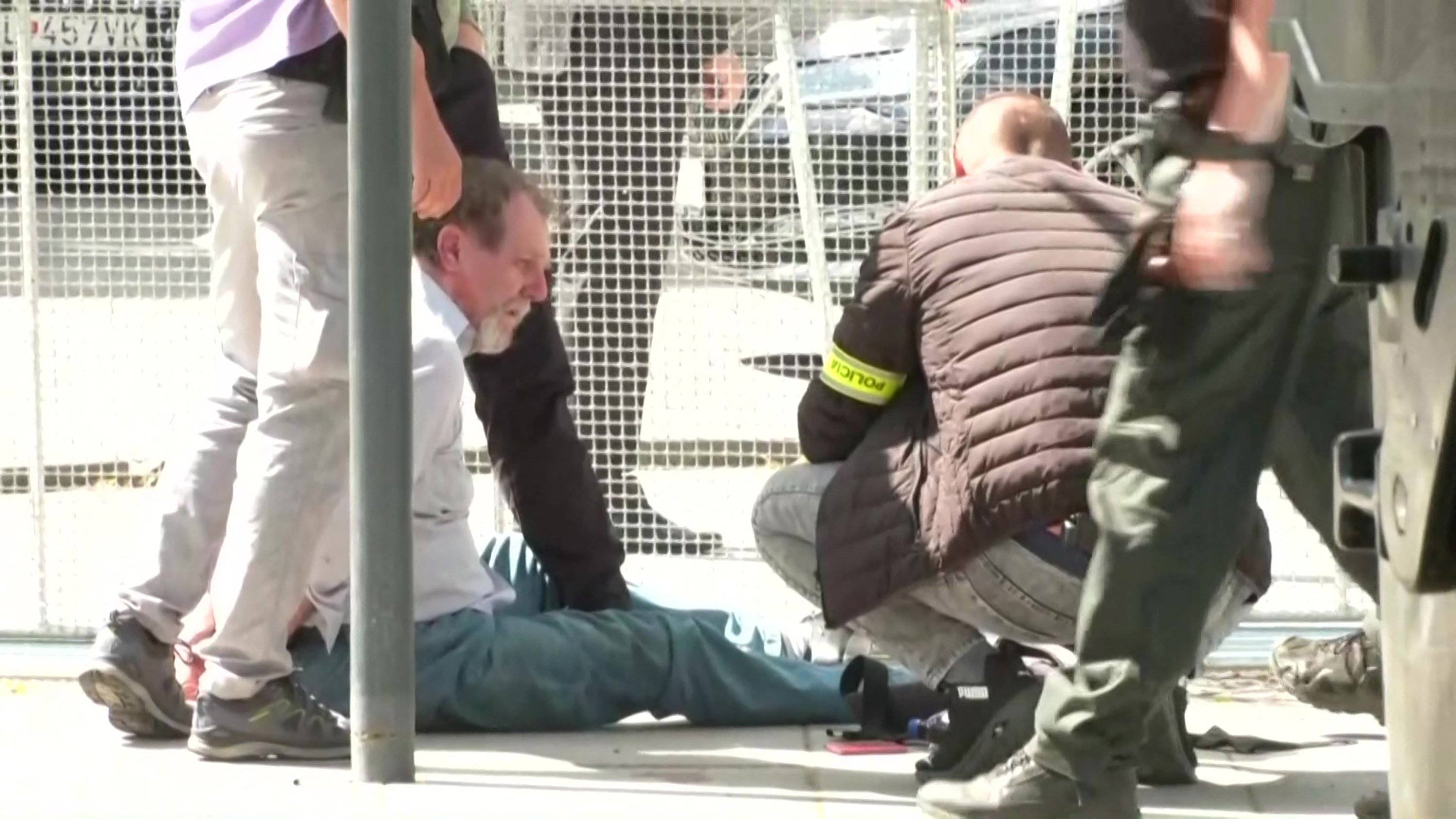 zamachowiec na życie Roberta Ficy siedzi na ziemi obezwładniony przez policję