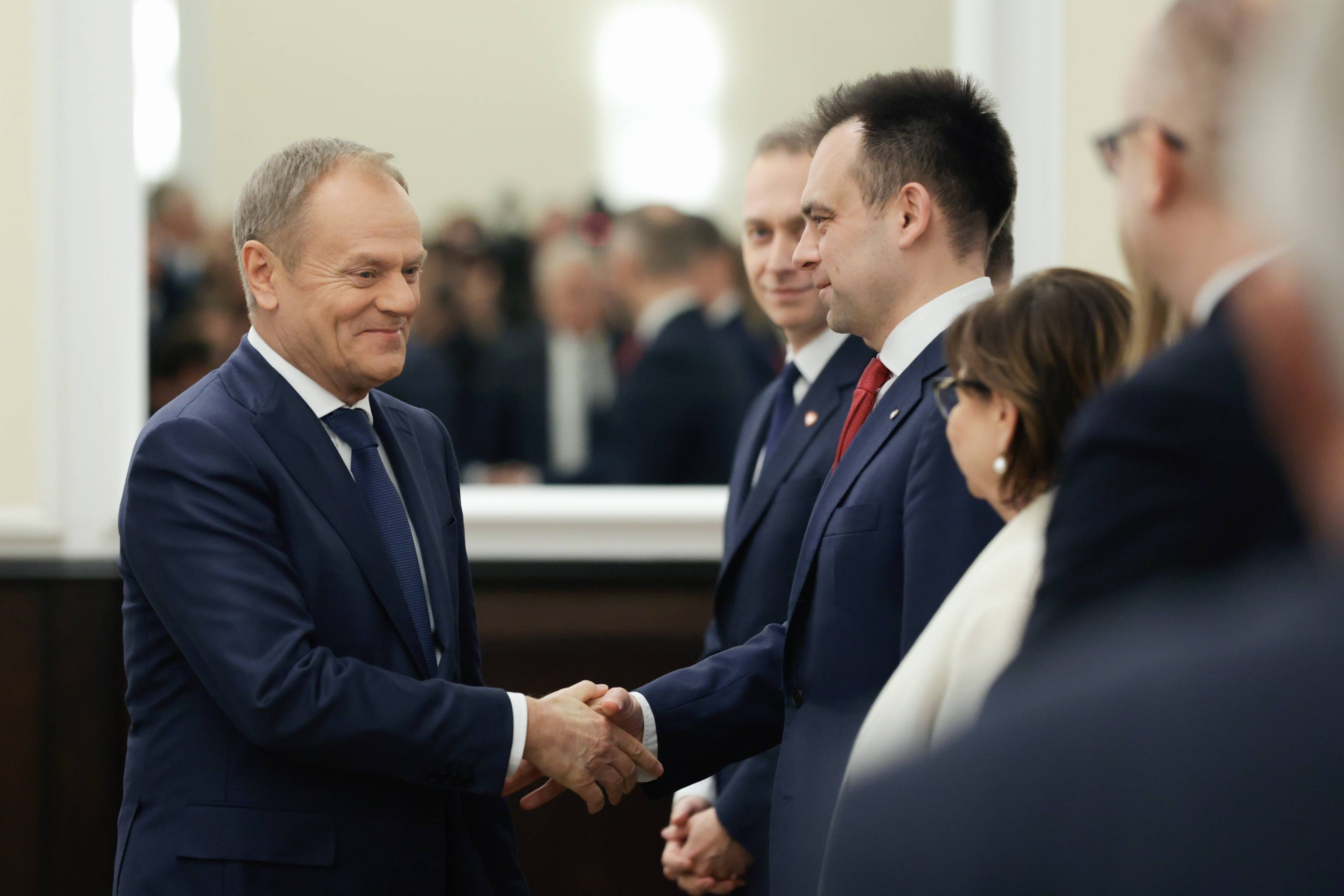 Premier Donald Tusk ściska dłoń ministra finansów Andrzeja Domańskiego