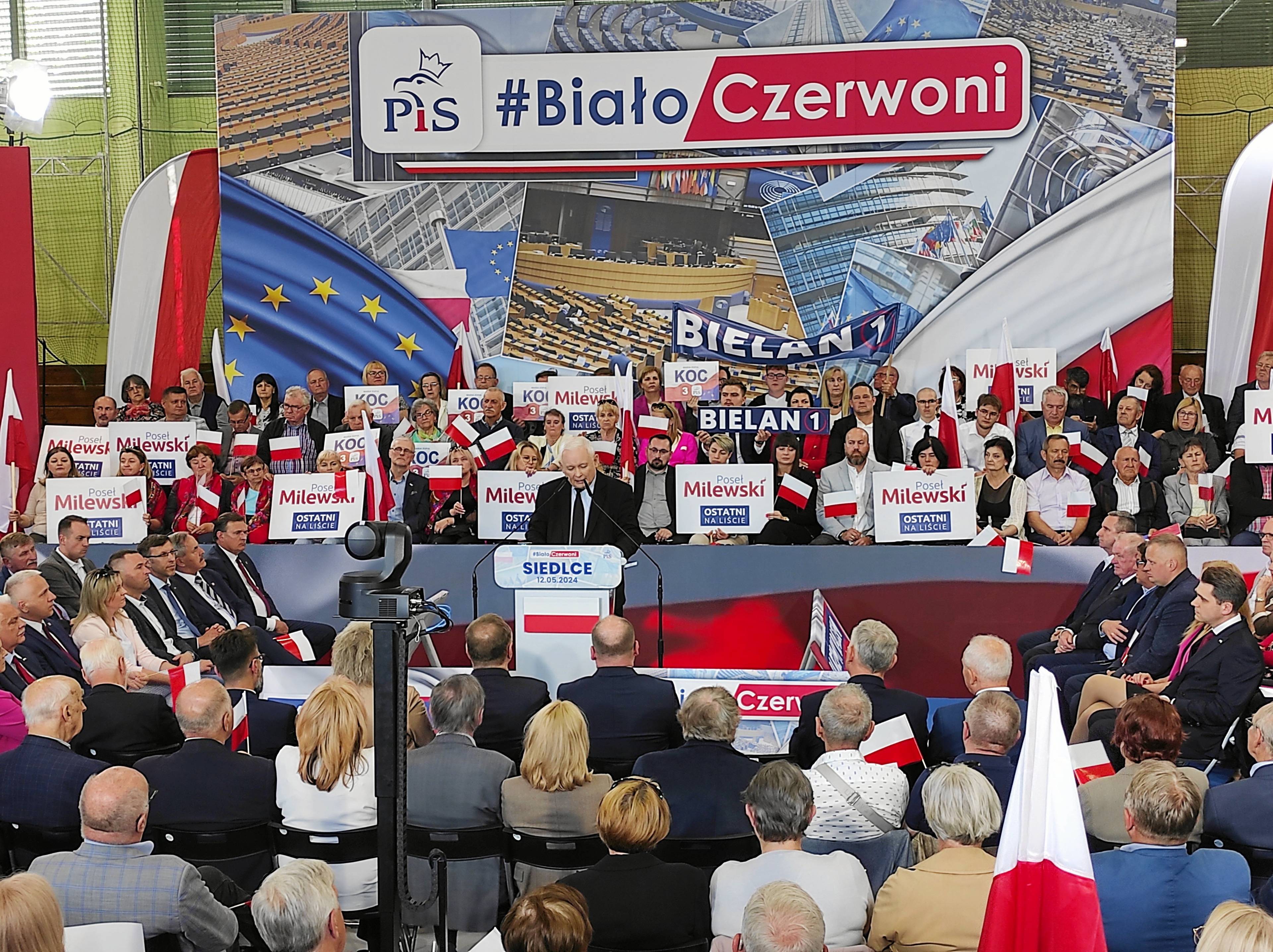 Jarosław Kaczyński, na pierwszym planie tłum ludzi, za nim transparent z napisem „#BiałoCzerwoni”