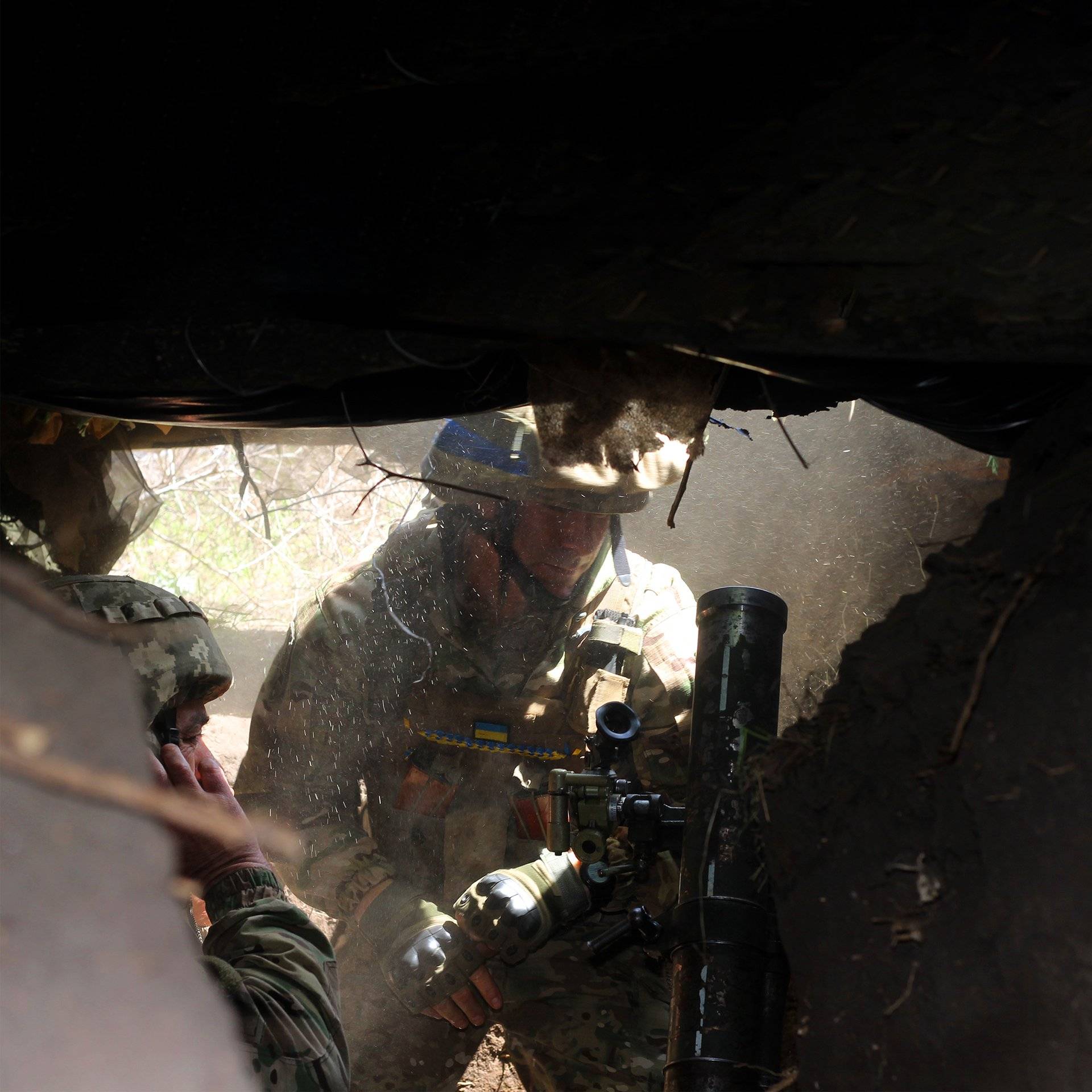 na zdjęciu dwóch żołnierzy w polowych mundurach ładuje moździerz ukryty w okopie. Konstantynówka, Ukraina