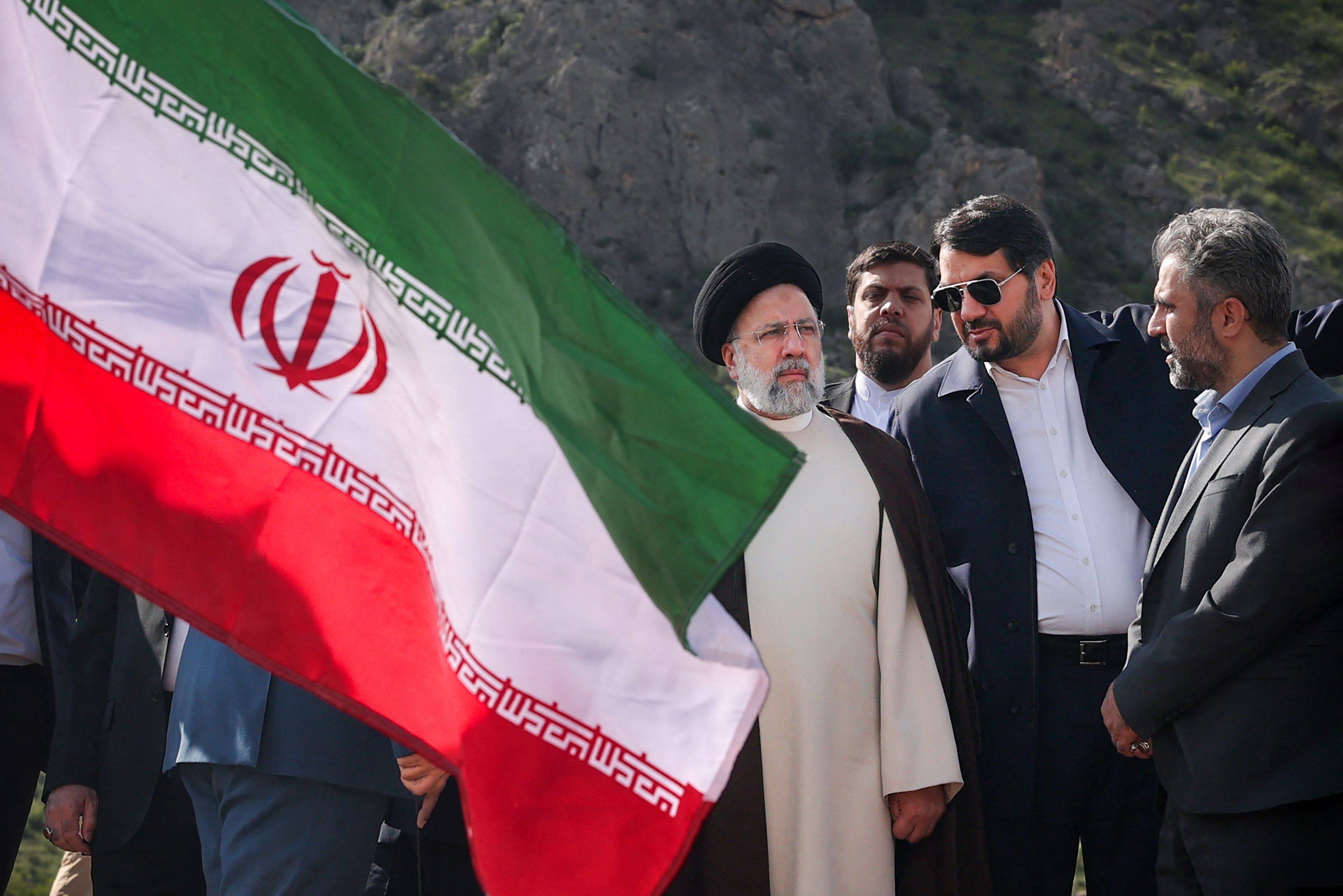 Prezydent Iranu stoi w otoczeniu mężczyzn na budowie tamy, obok widać flagę irańską