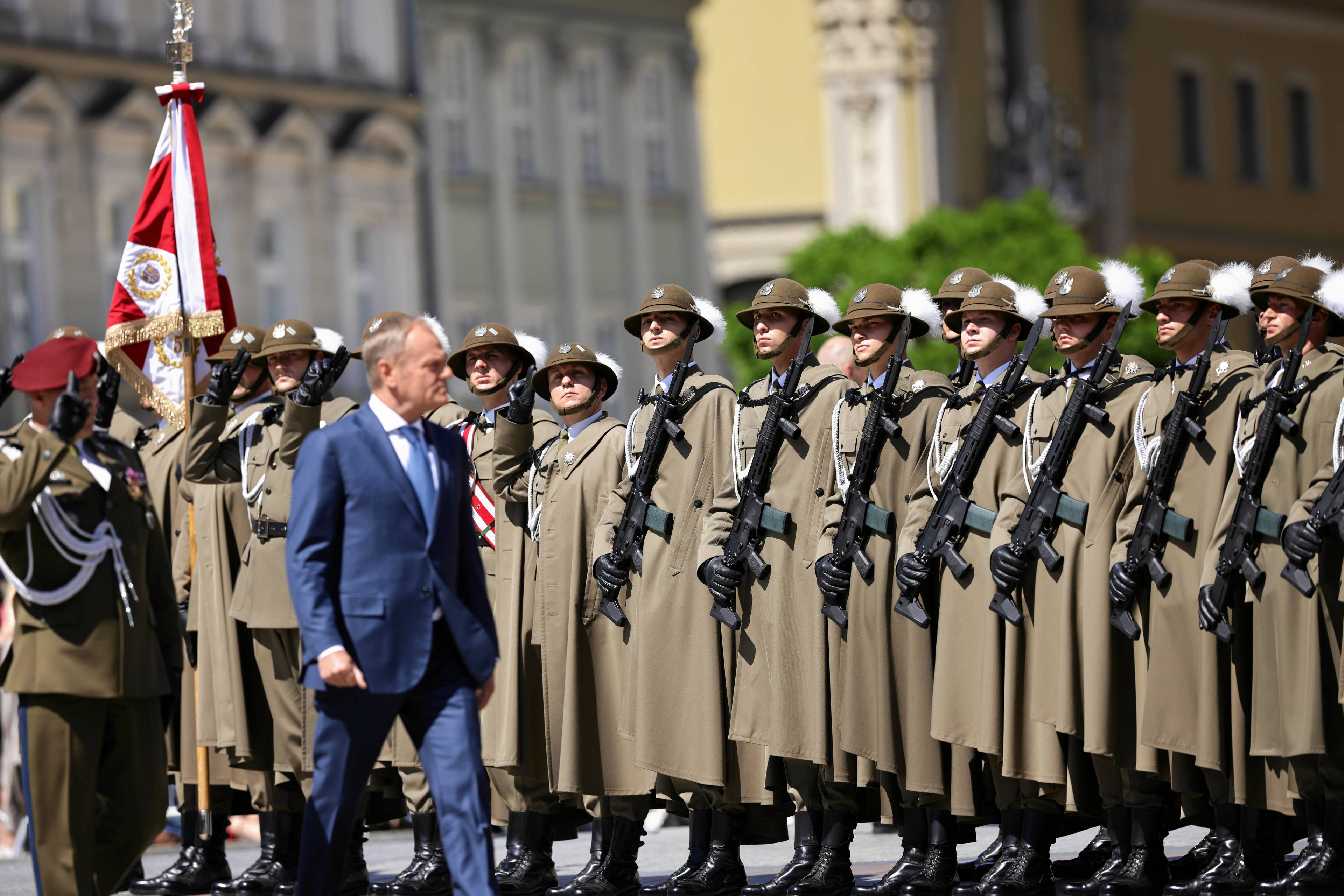 Premier Donald Tusk maszeruje na tle żołnierzy ustawionych w szeregu na krakowskim rynku