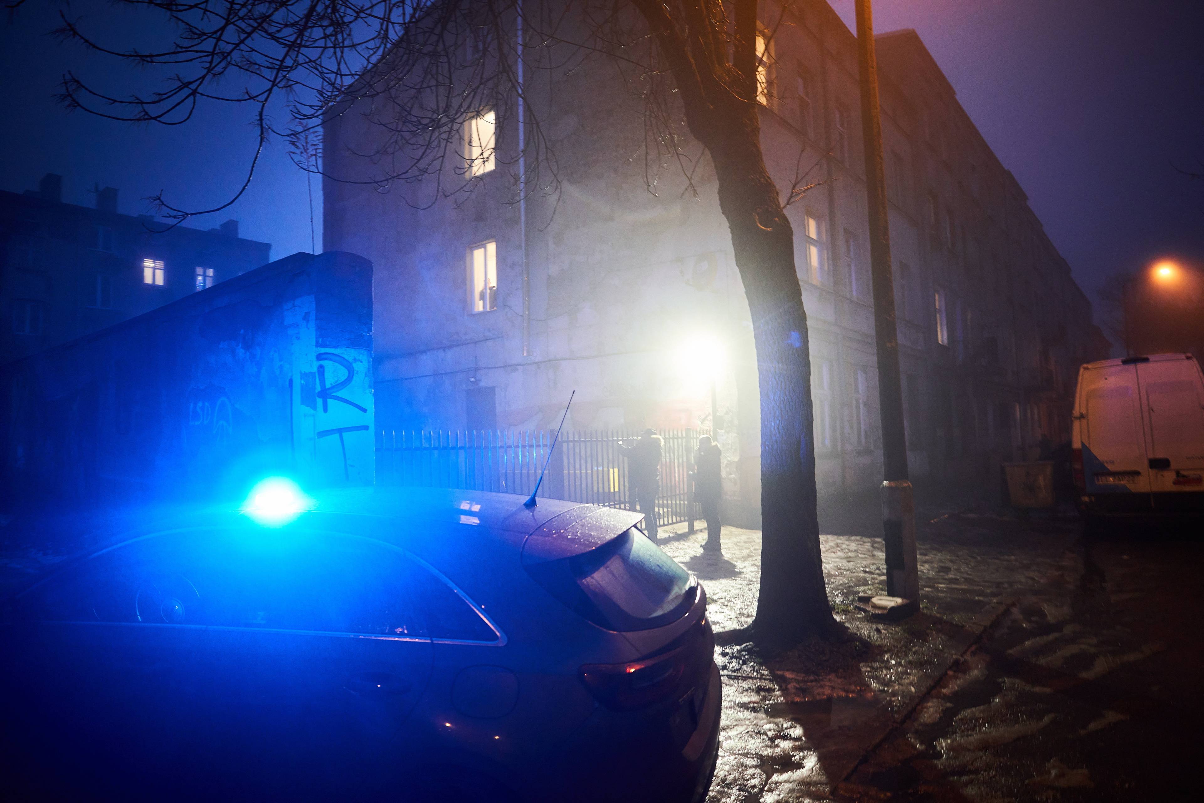 Samochód policyjny z intensywnie niebieskim światłem pod domem o zmierzchu