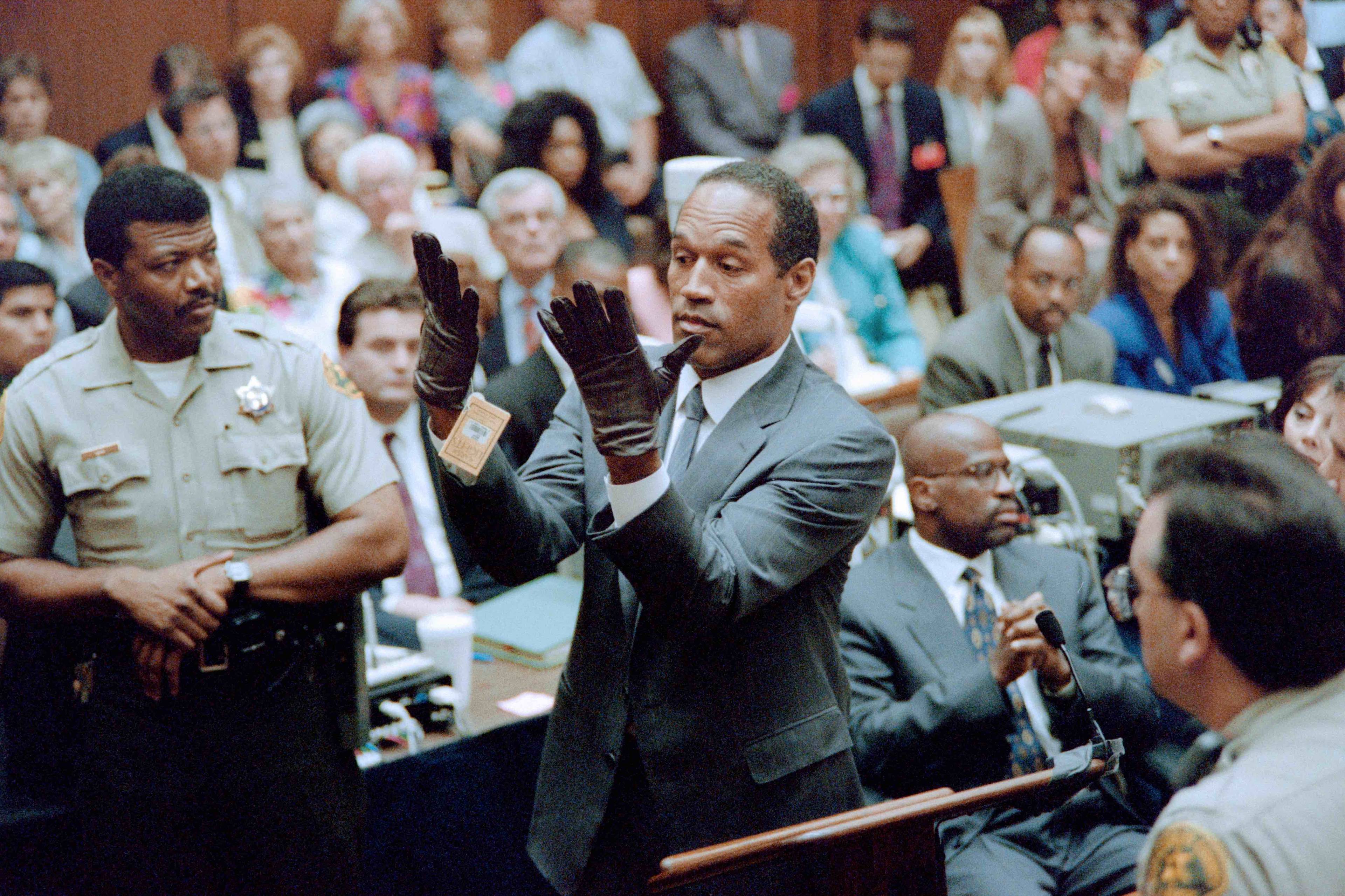 O.J. Simpson podnosi dłonie w czarnych rękawiczkach na sali sądowej