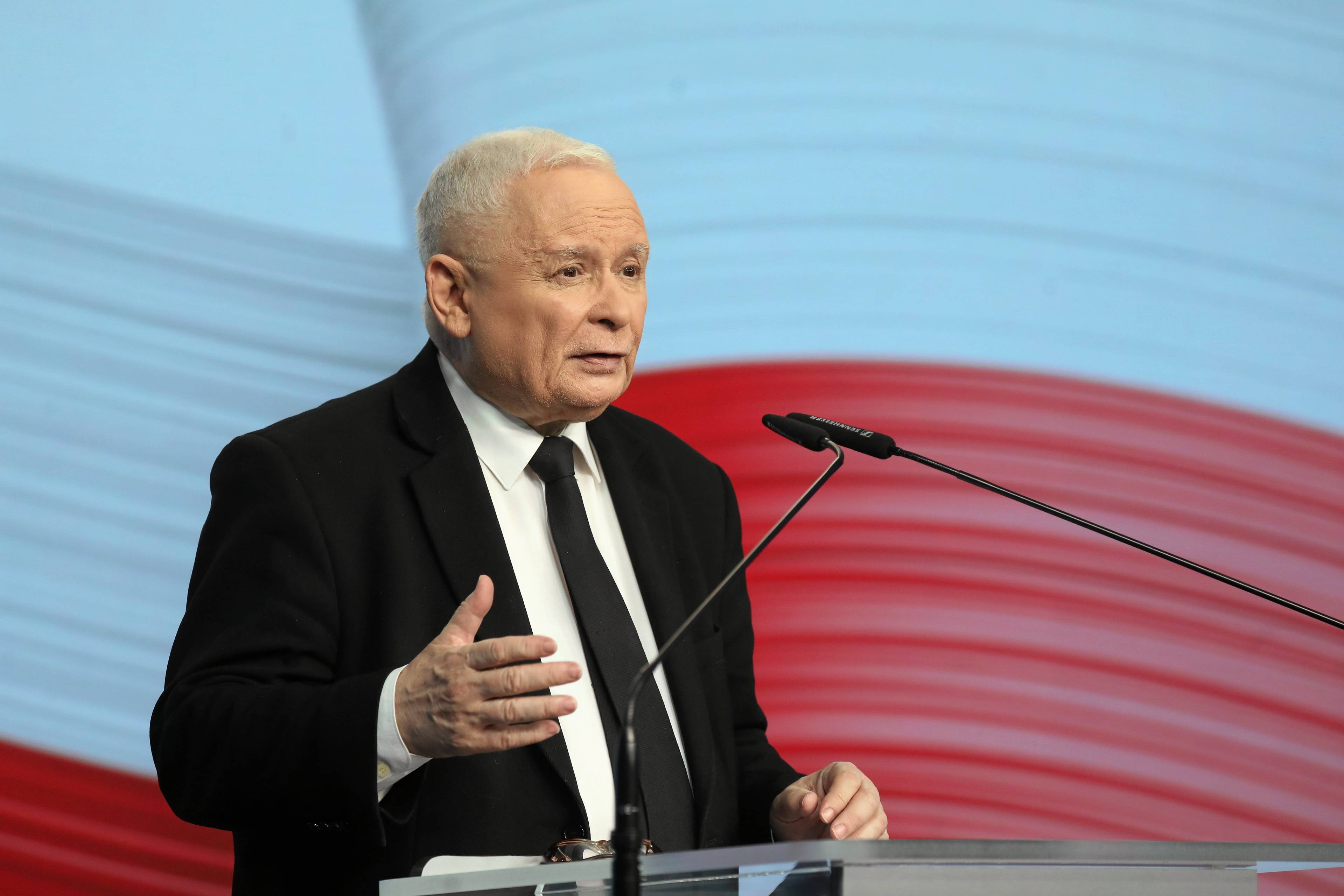 Kaczyński na tle biało czerwonej flagi