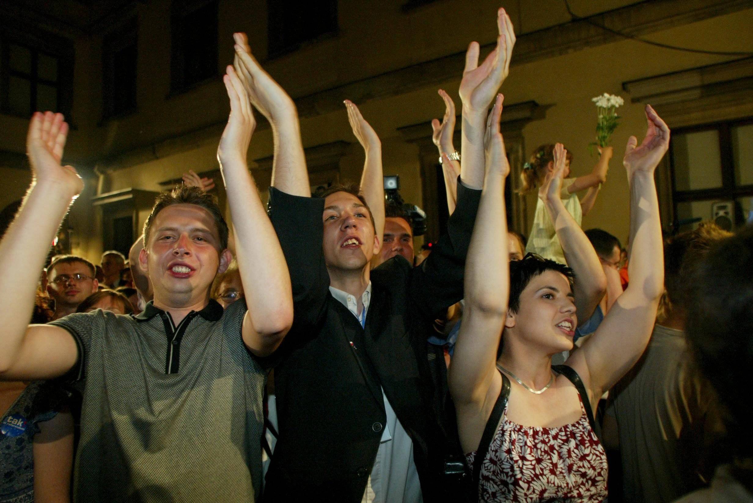 młodzi ludzie z rękami podniesionymi w góre w geście euforii