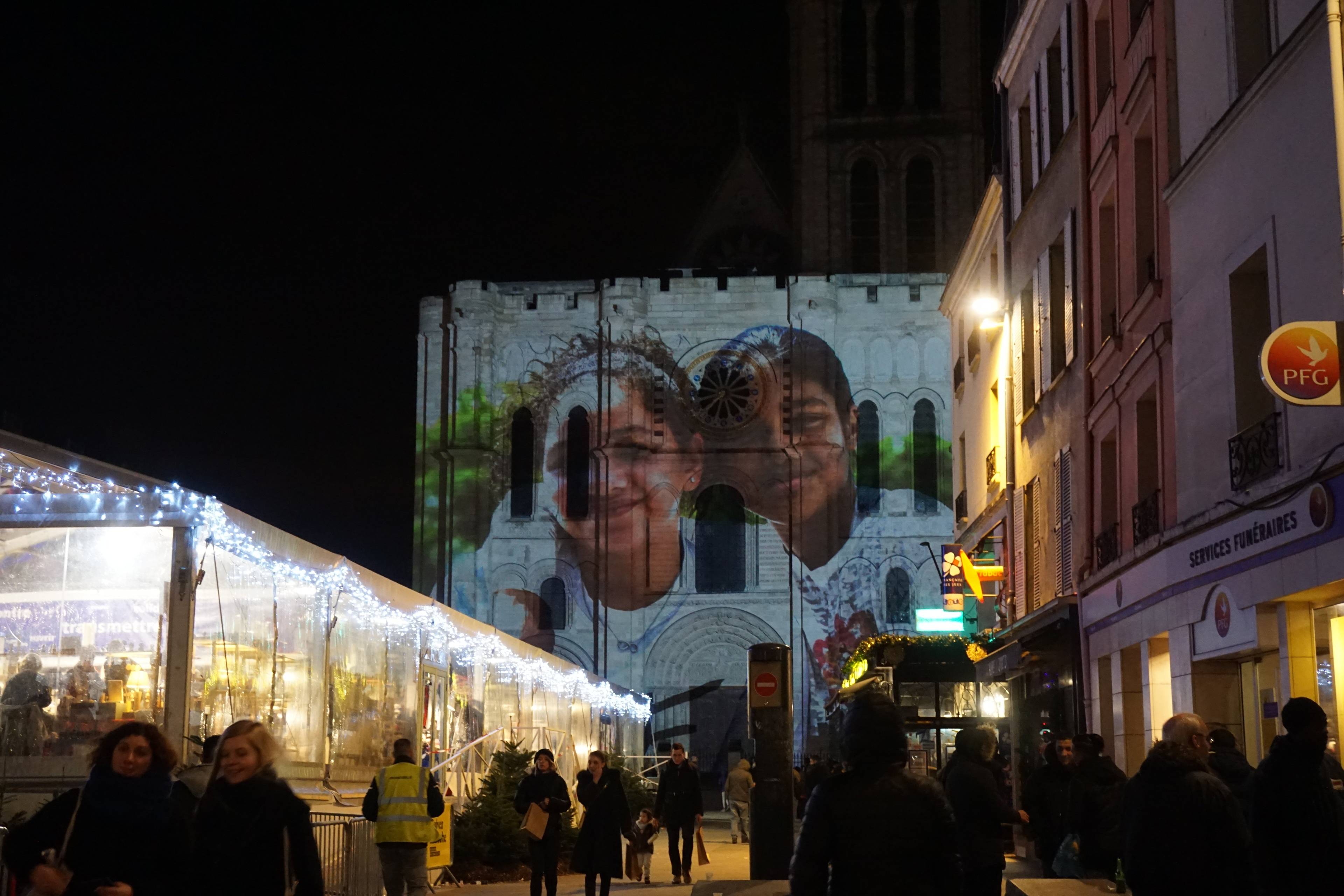 twarze ciemnoskórych dziewczynek wyświetlone na gotyckiej fasadzie kościoła