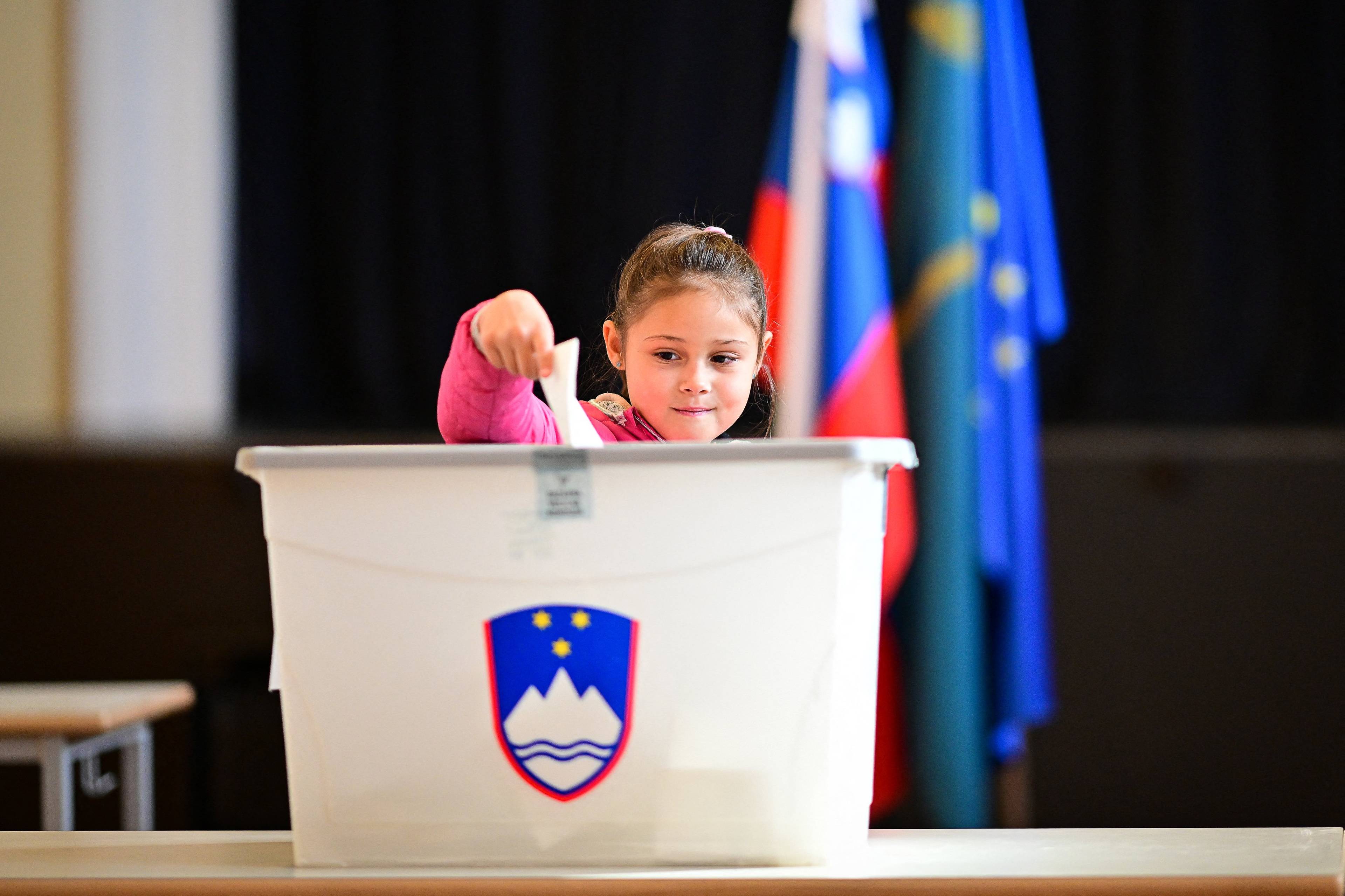 Młoda dziewczynka wrzuca głos do urny wyborczej podczas wyborów w Słowenii