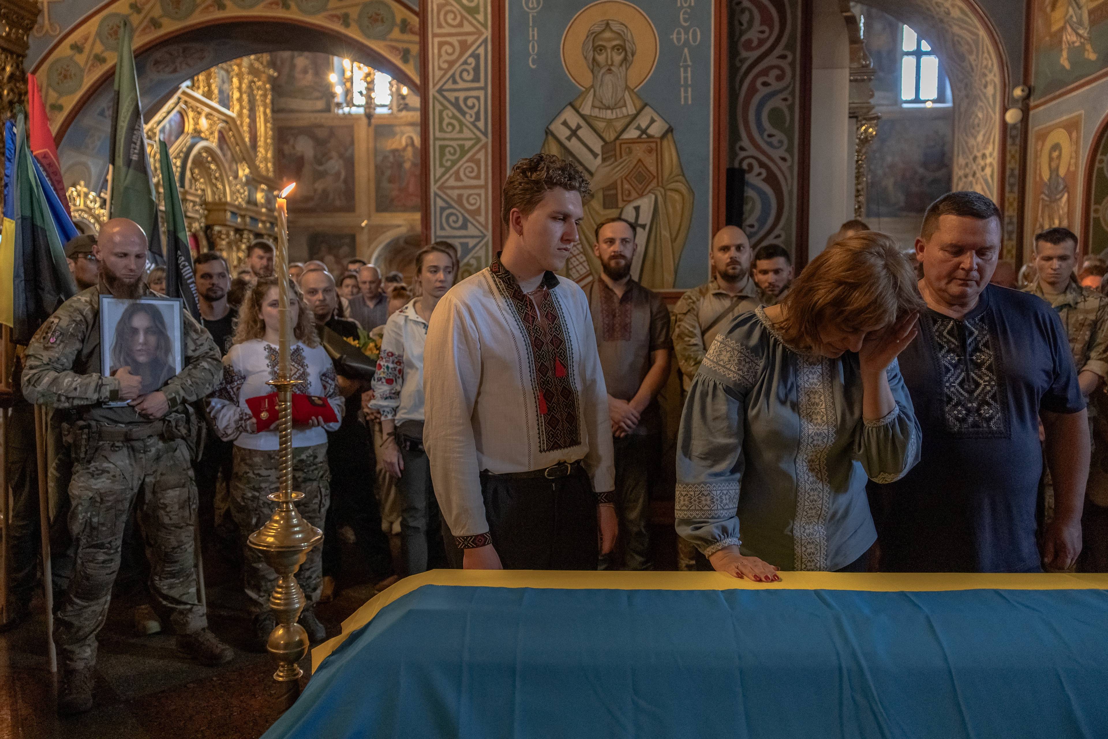 Na zdjęciu w cerkwi obok trumny przykrytej flagą żółto-niebieską stoi rodzina Iryny Cybuch: brat Jurij z matką oraz ojcem. Są w koszulach wyszywanych. W tle są inni ludzie