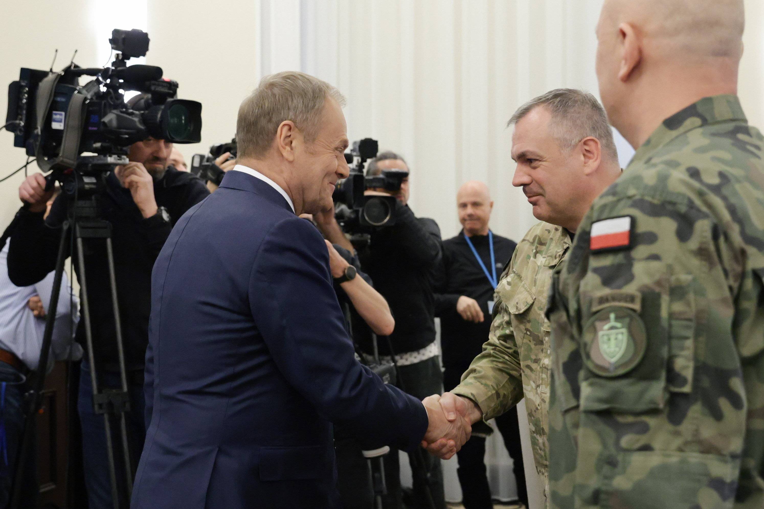 Premier Donald Tusk ściska dłoń wojskowego podczas posiedzenia Rady Ministrów