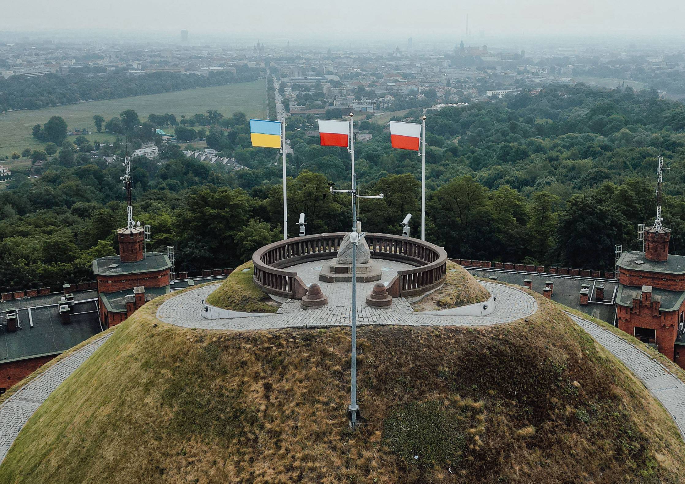 Trzy flagi: jedna ukraińska i dwie polskie, powiewają na masztach na Kopcu Kościuszki w Krakowie