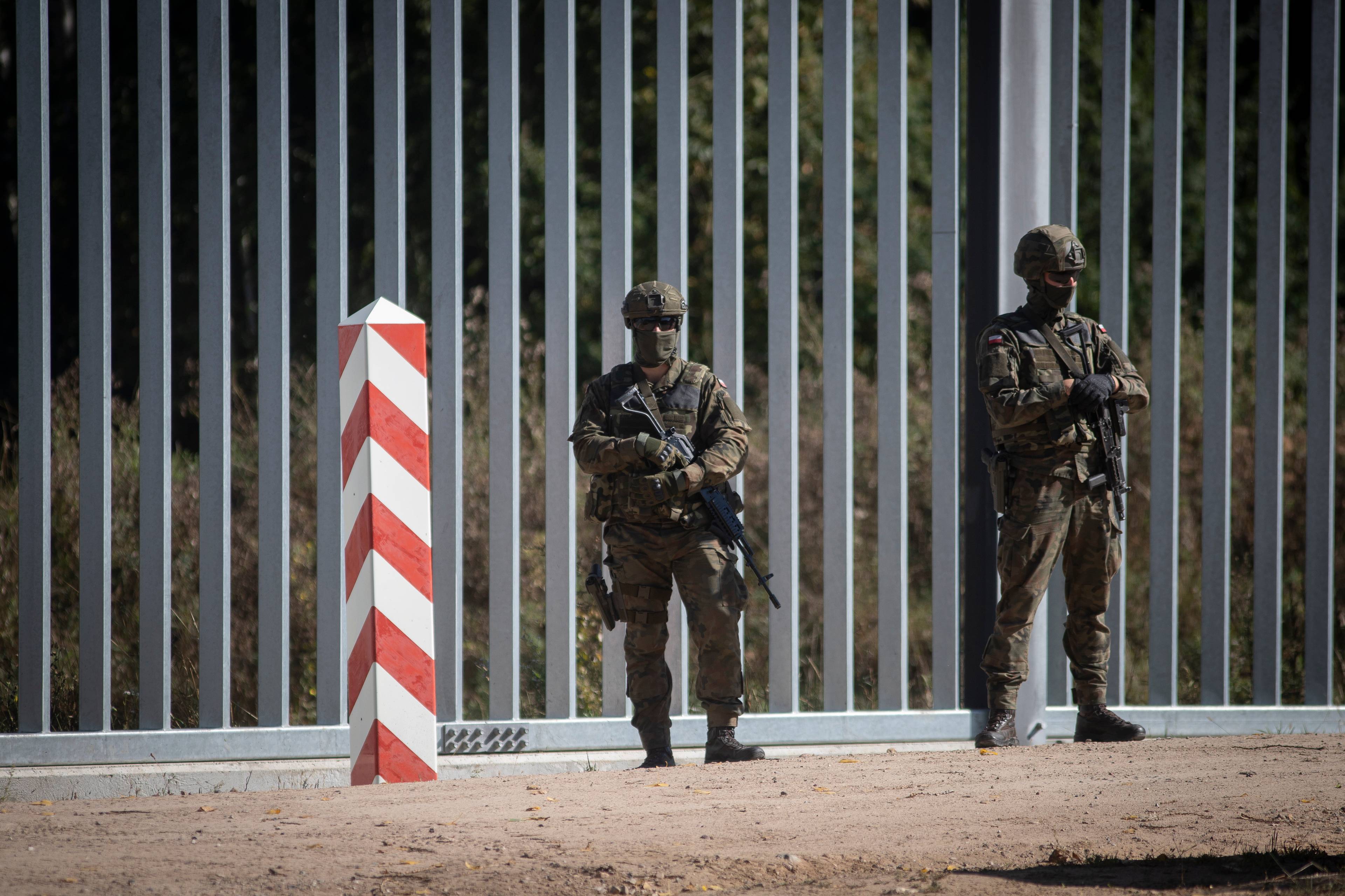 żołnierze w pełnym umundurowaniu przy płocie granicznym