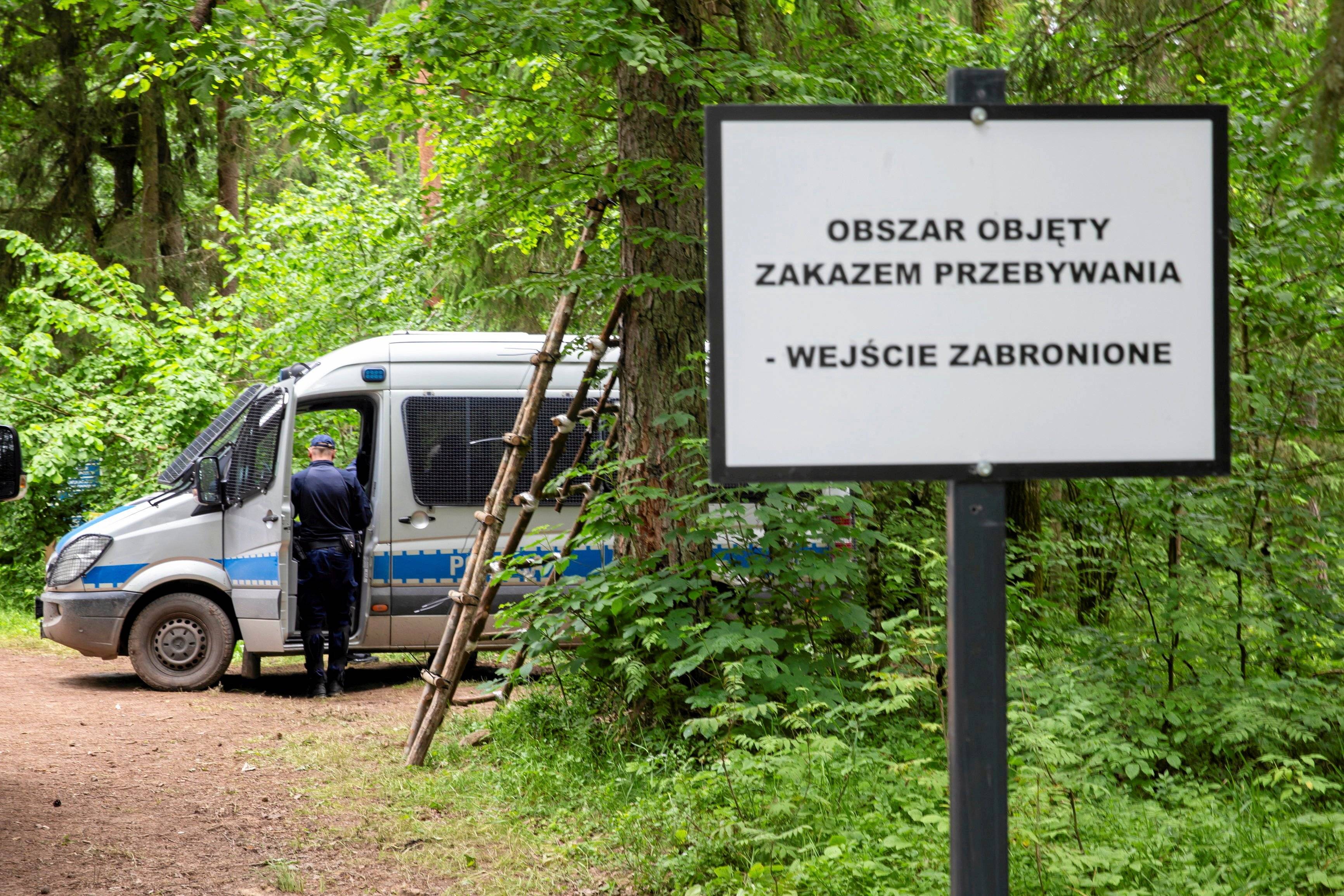 Samochód policyjny i tablica w lesie: strefa objęta zakazem przebywania