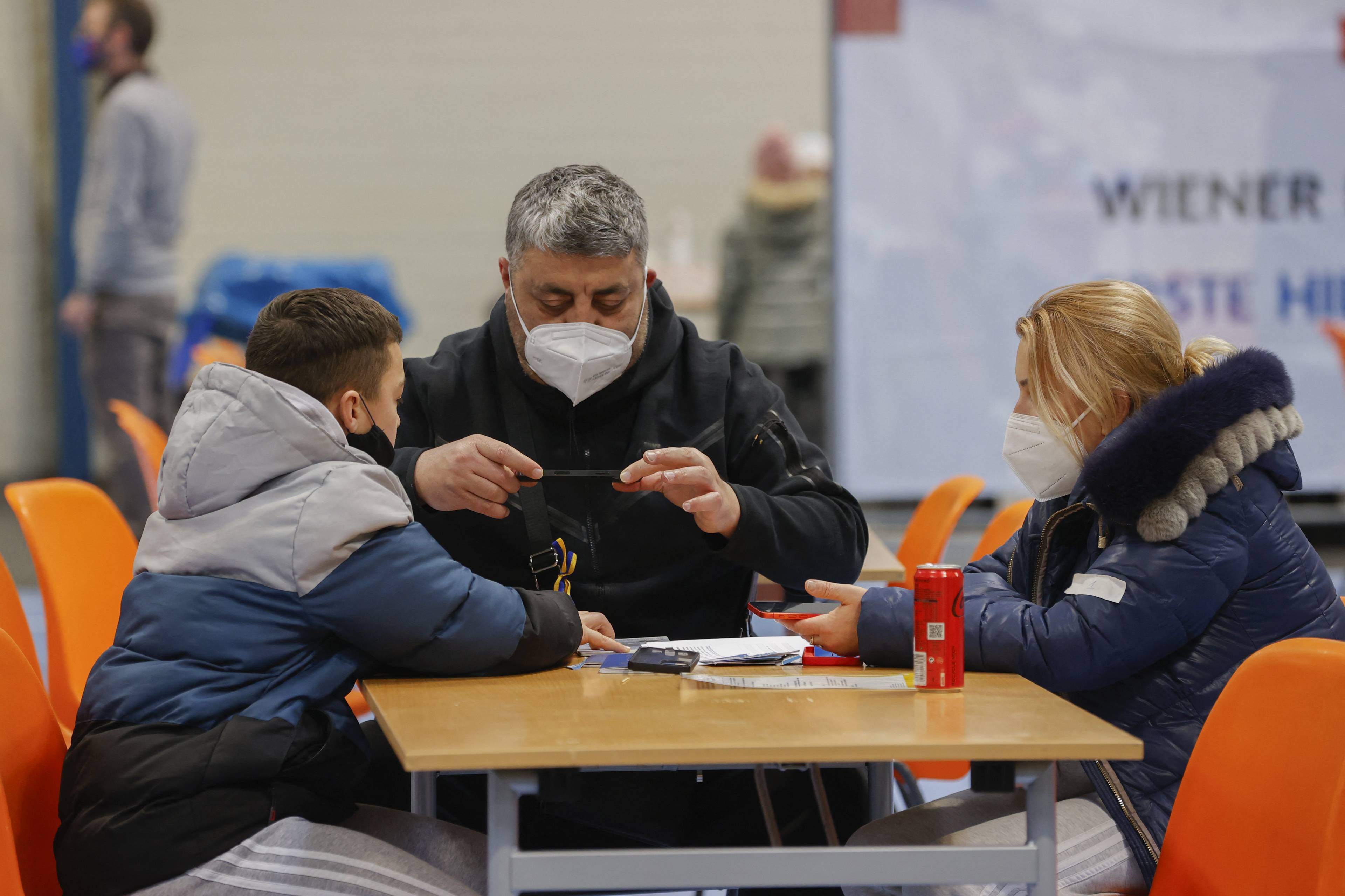 People sit at a table at a temporary reception centre for refugees from Ukraine in Vienna, on March 4, 2022. (Photo by Benedikt LOEBELL / APA / AFP) / Austria OUT