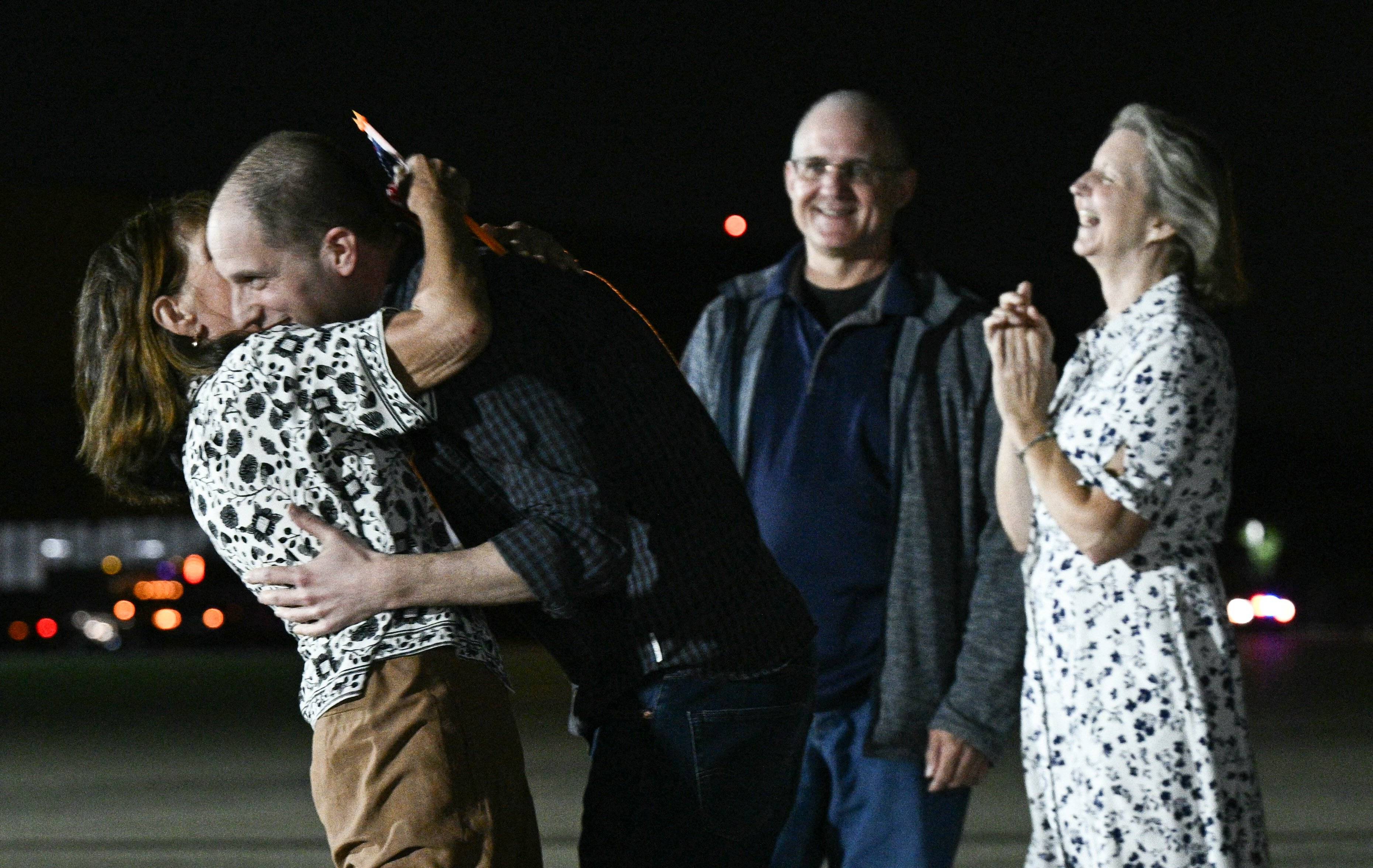 Former US Marine Paul Whelan and his sister Elizabeth Whelan watch as US journalist Evan Gershkovich hugs his mother Ella Milman at Joint Base Andrews in Maryland on August 1, 2024. Journalist Evan Gershkovich and fellow prisoners released by Russia landed in the United States late August 1, an AFP journalist saw, as part of an extraordinary swap deal struck between Washington and Moscow. 
A plane carrying Gershkovich, former US marine Paul Whelan, and journalist Alsu Kurmasheva landed at around 11:40 pm (0340 GMT) at Joint Base Andrews near Washington, where President Joe Biden and Vice President Kamala Harris were waiting to greet them. (Photo by Brendan SMIALOWSKI / AFP)