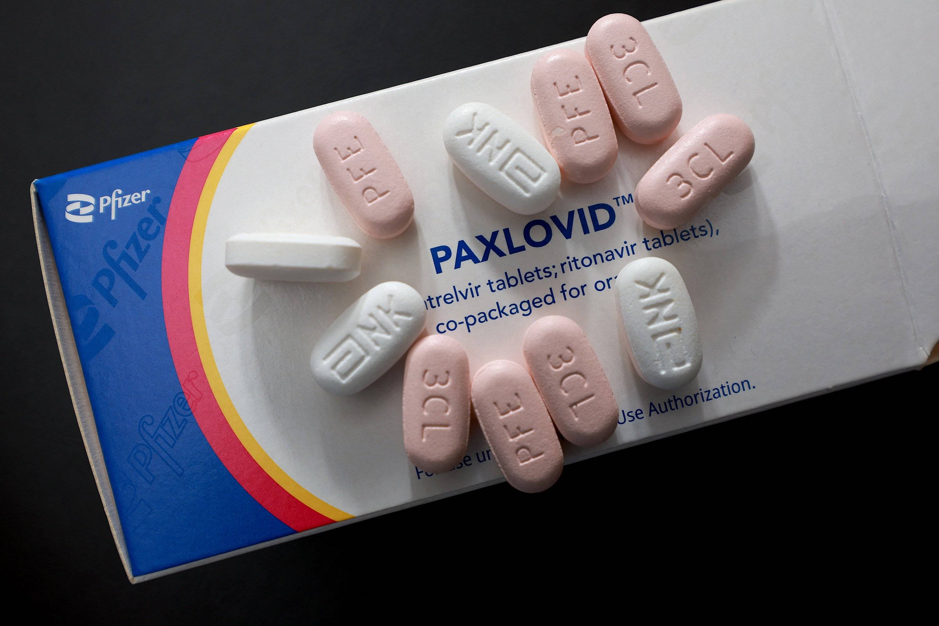 Opakowanie leku Paxlovid, na nim białe i różowe tabletki