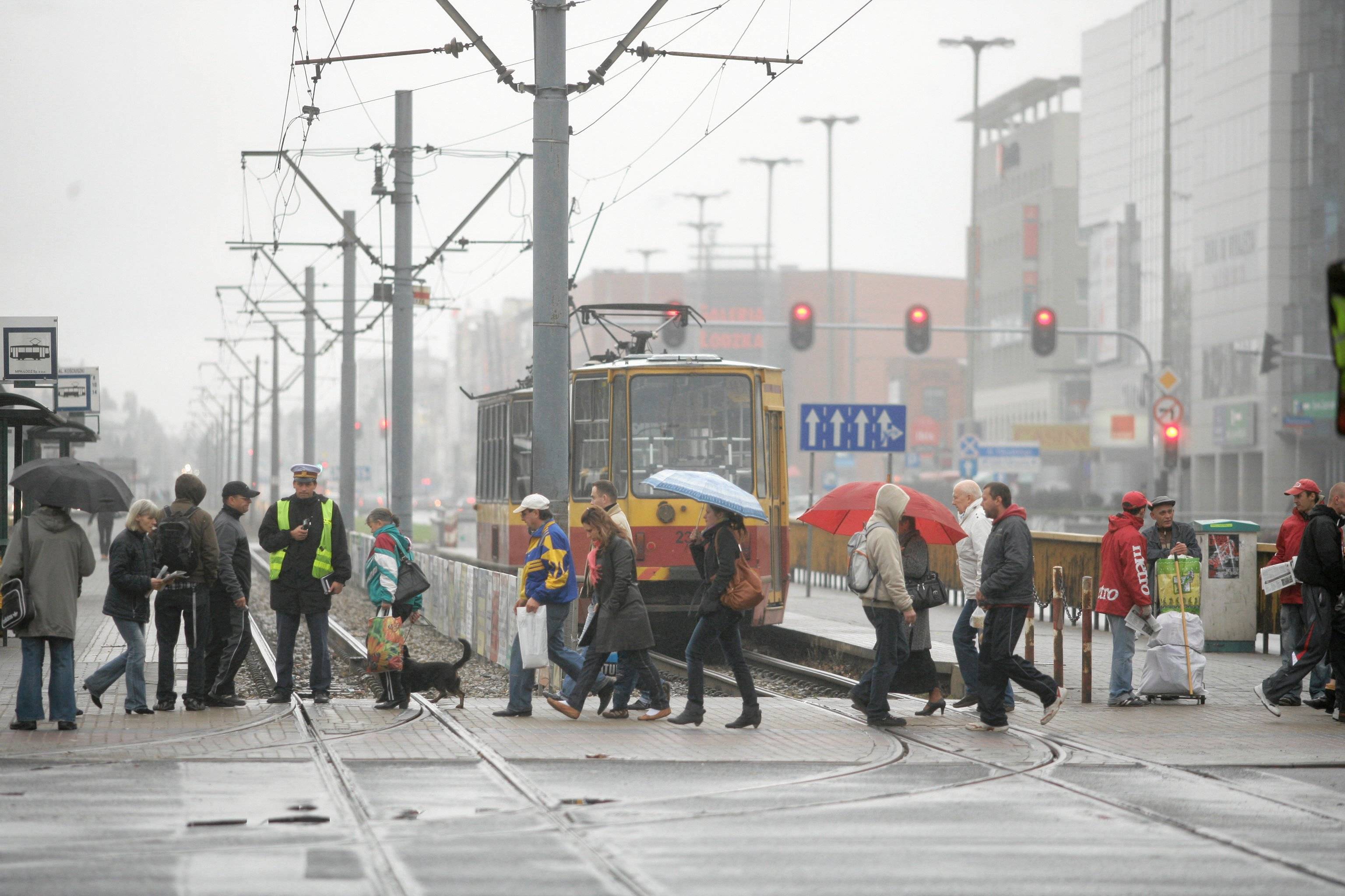 Ludzie przechodzą przez jezdnię, stoi tramwaj