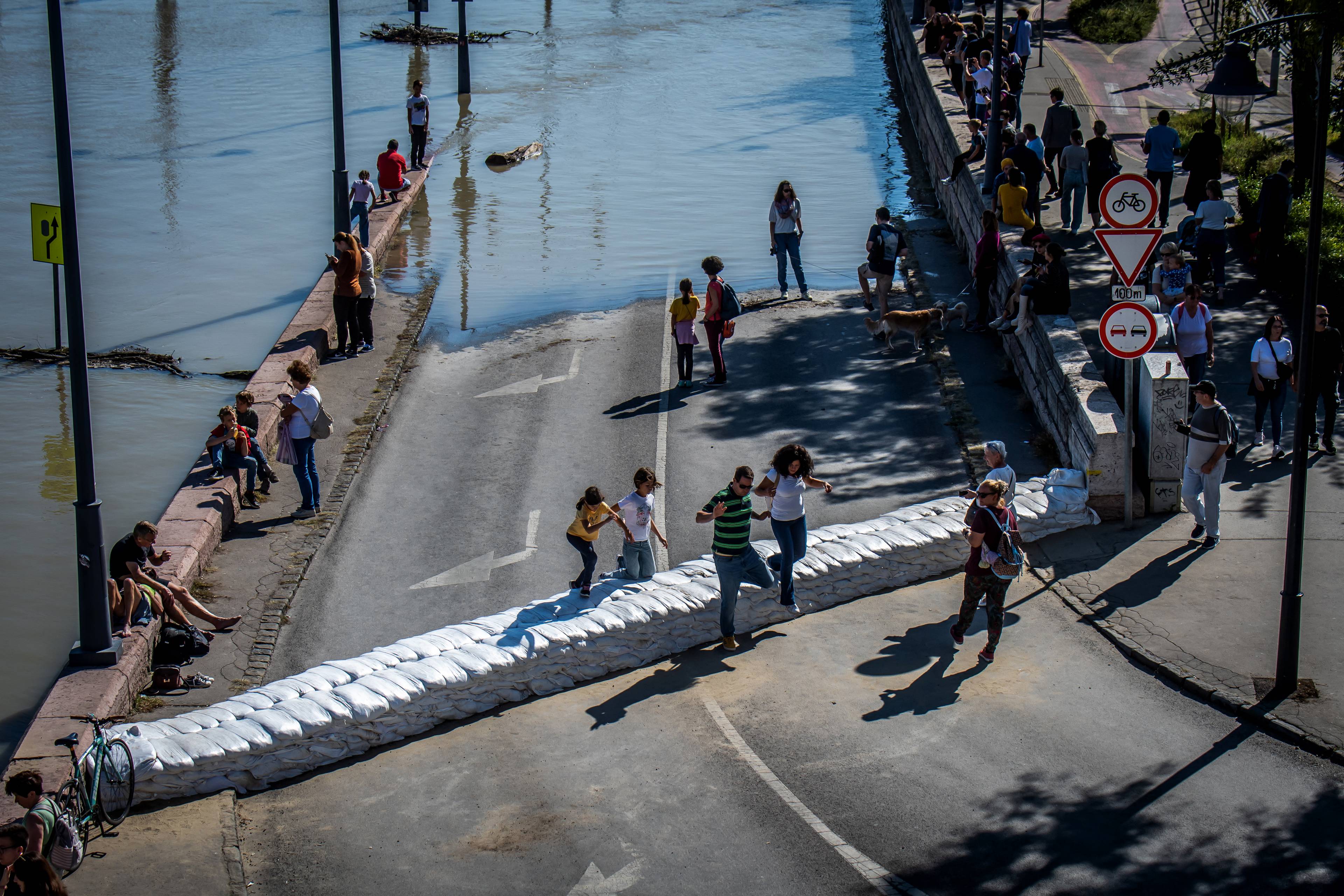 Onlookers walk over a barrier made of sandbags set up for protection against floodwater as the Danube floods the river bank in Budapest, Hungary, on September 21, 2024, reaching its peak and marking a 10-year high, after deadly storm Boris lashed Europe. Torrential rains and strong winds have led to widespread flooding in central and eastern Europe since last week, killing 24 people and devastating towns and villages. (Photo by FERENC ISZA / AFP)