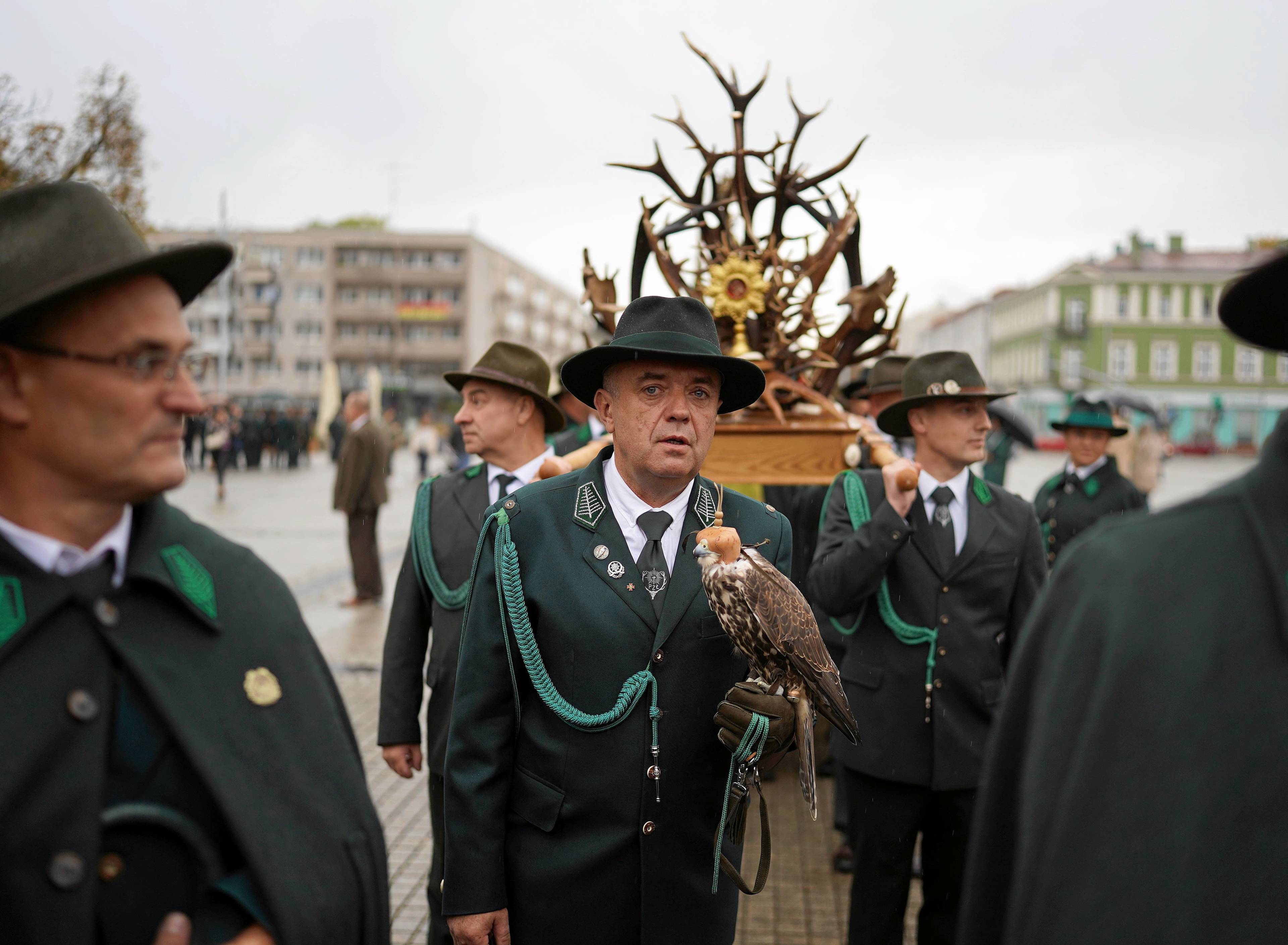 Myśliwi w zielonych mundurach niosą ołtarz z poroża