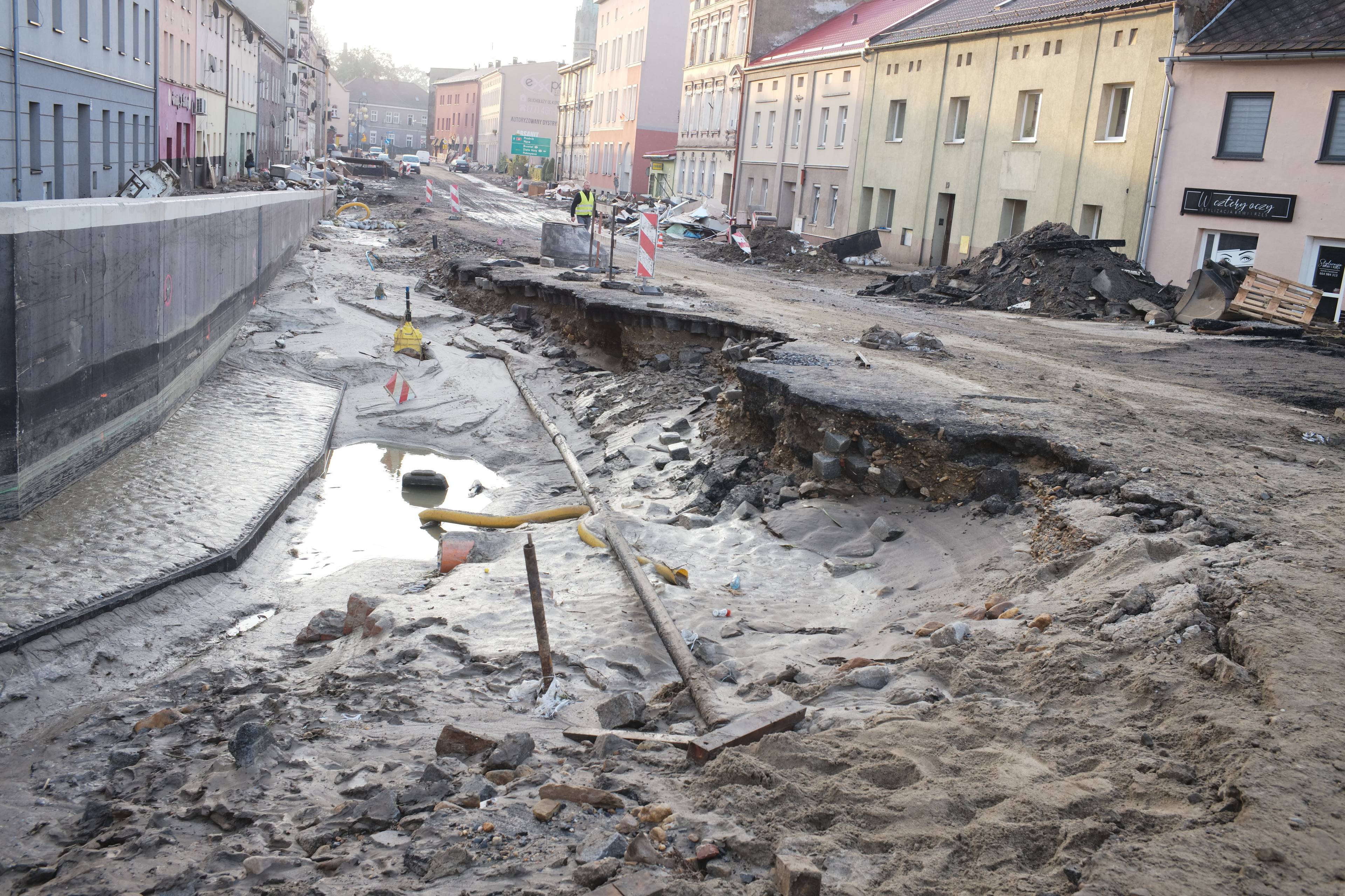 Ulica z wielką wyrwą pozostawioną przez powódź. Wzdłuż ulicy stare kamieniczki