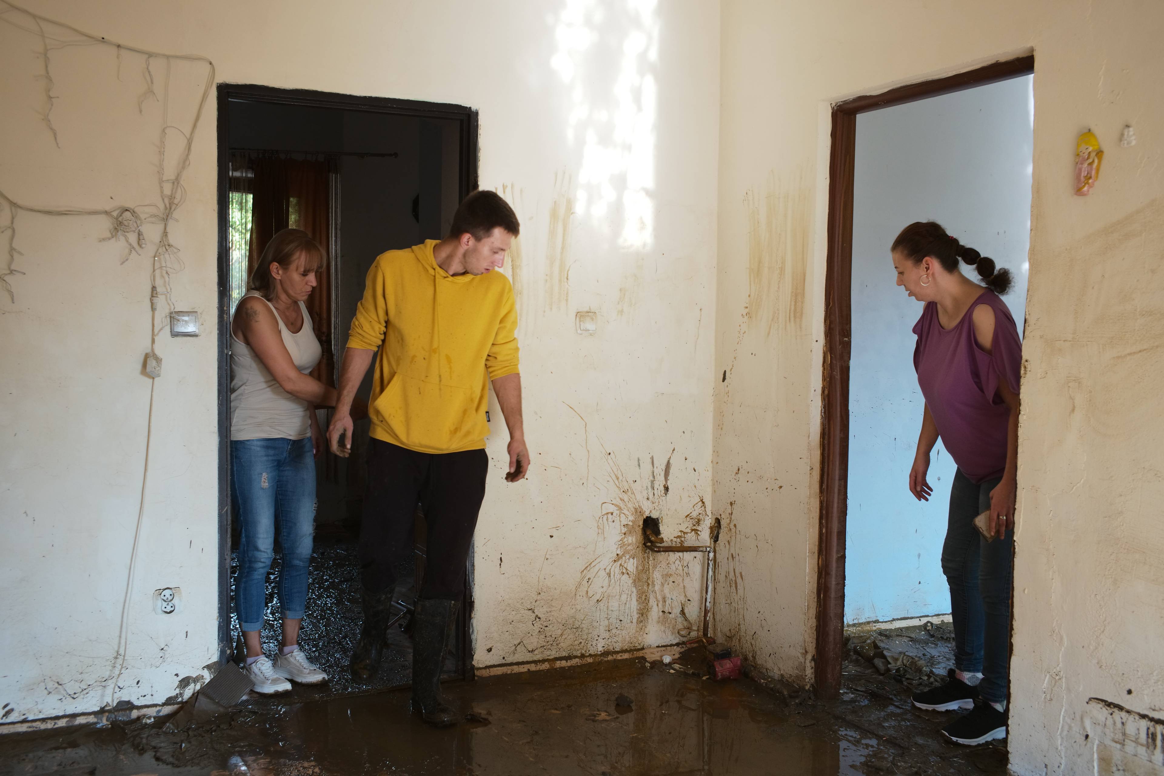 Dwie kobiety i mężczyzna stoją wewnątrz mieszkania zniszczonego powodzią