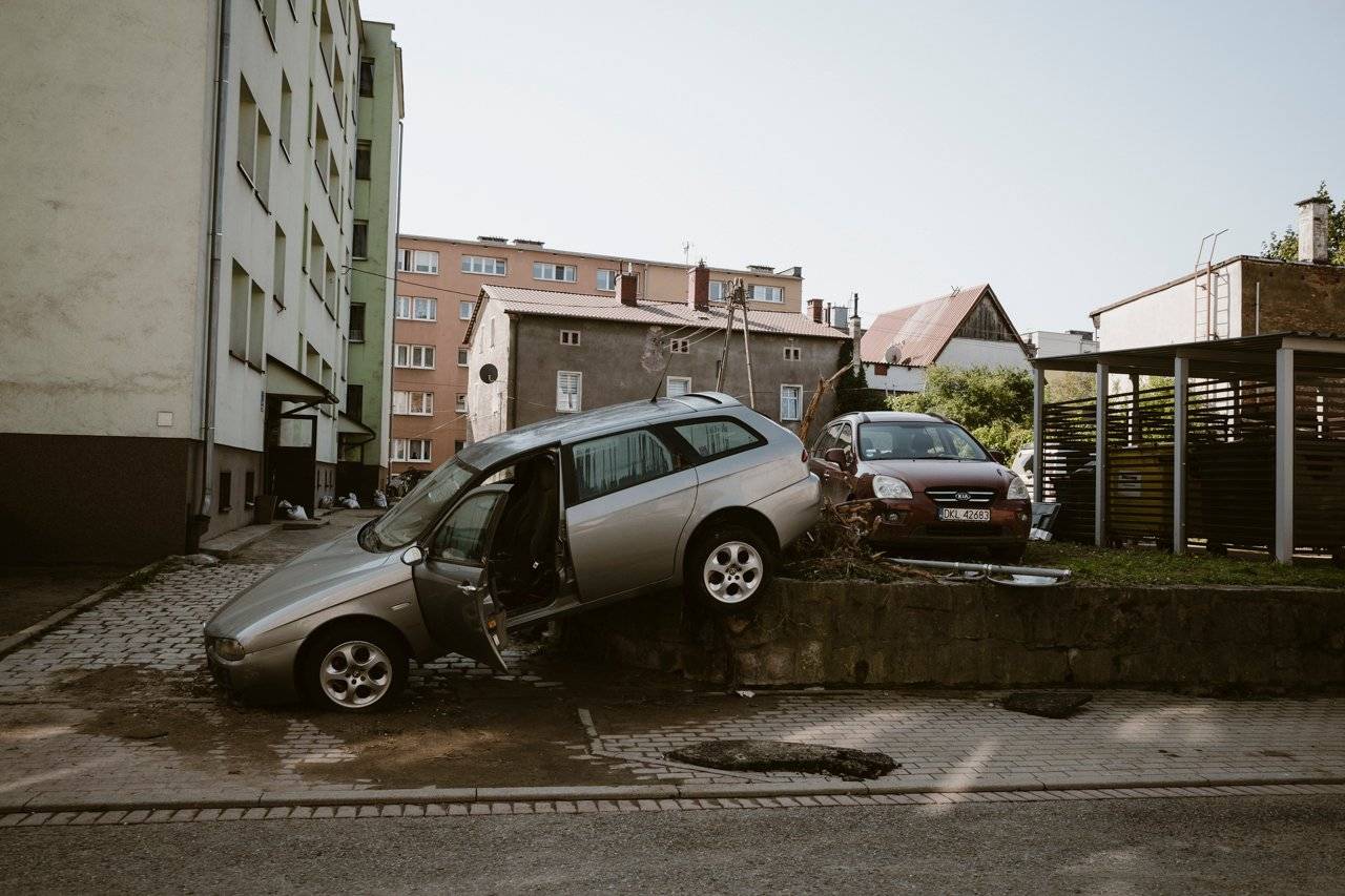 Samochody wyniesione przez falę powodziową na skwer przed blokiem.