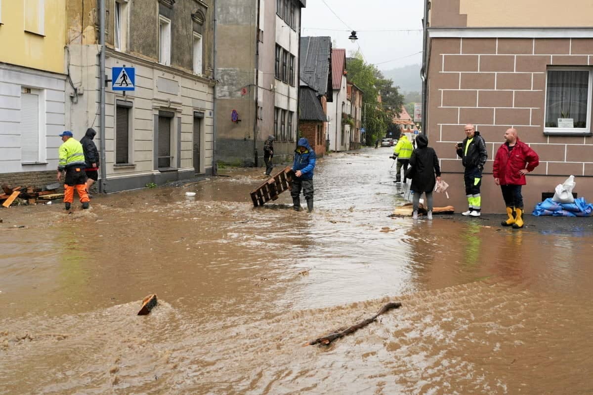 Zalane miasto, ludzie sprzątają płynące belki