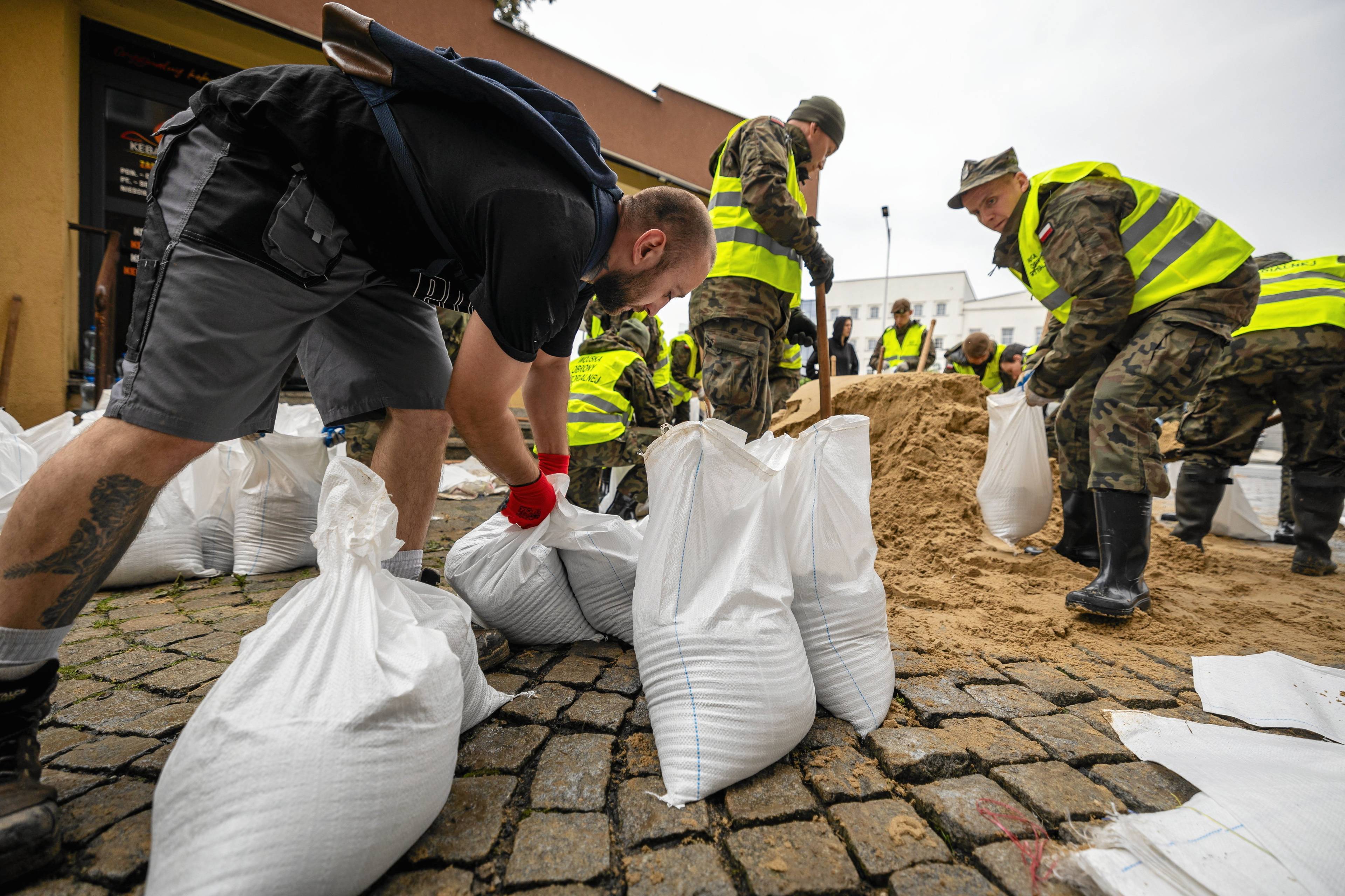 Ludzie układają worki z piaskiem zabezpieczające przed powodzią