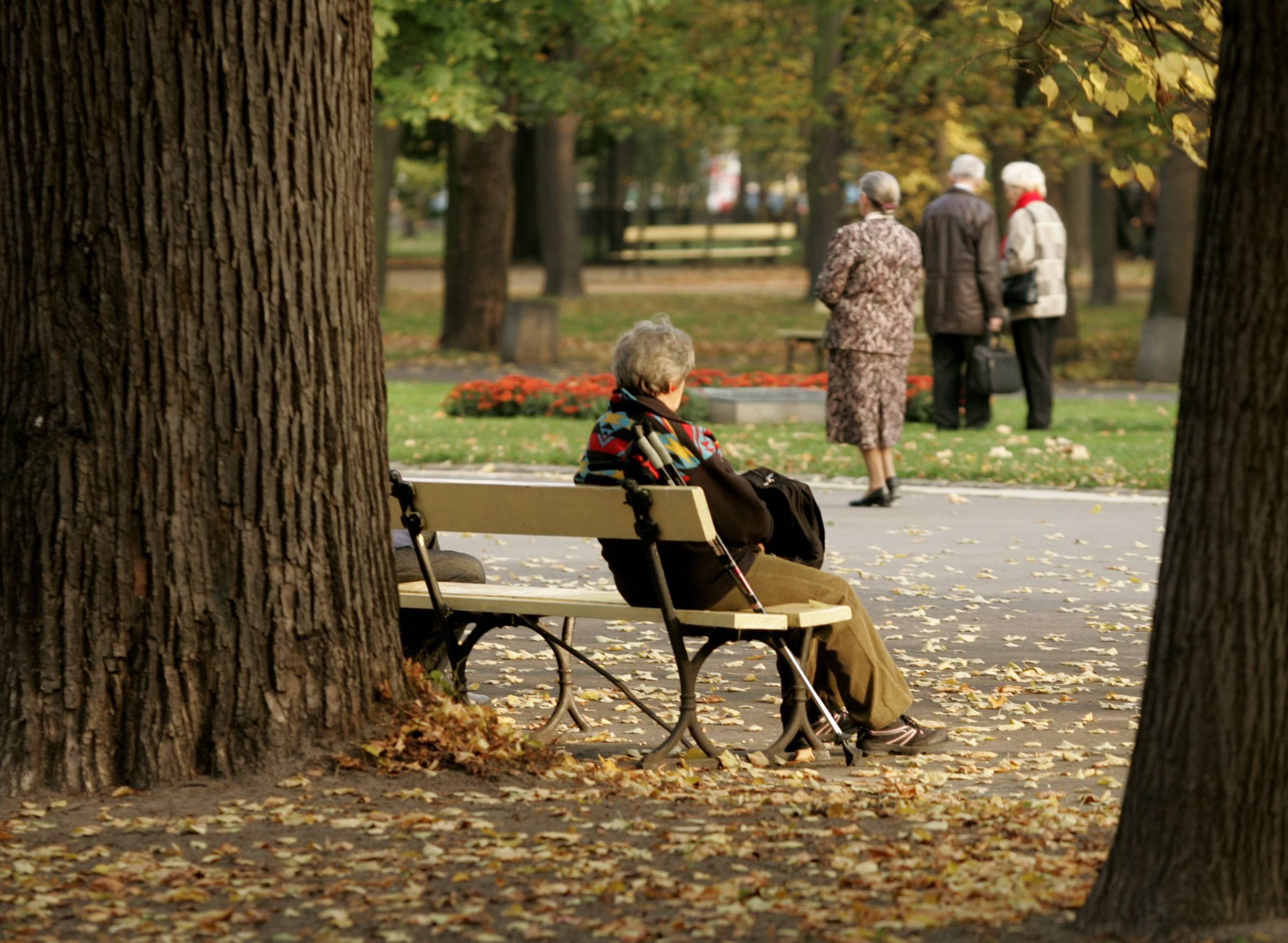 Samotna osoba siedzi na ławce w parku