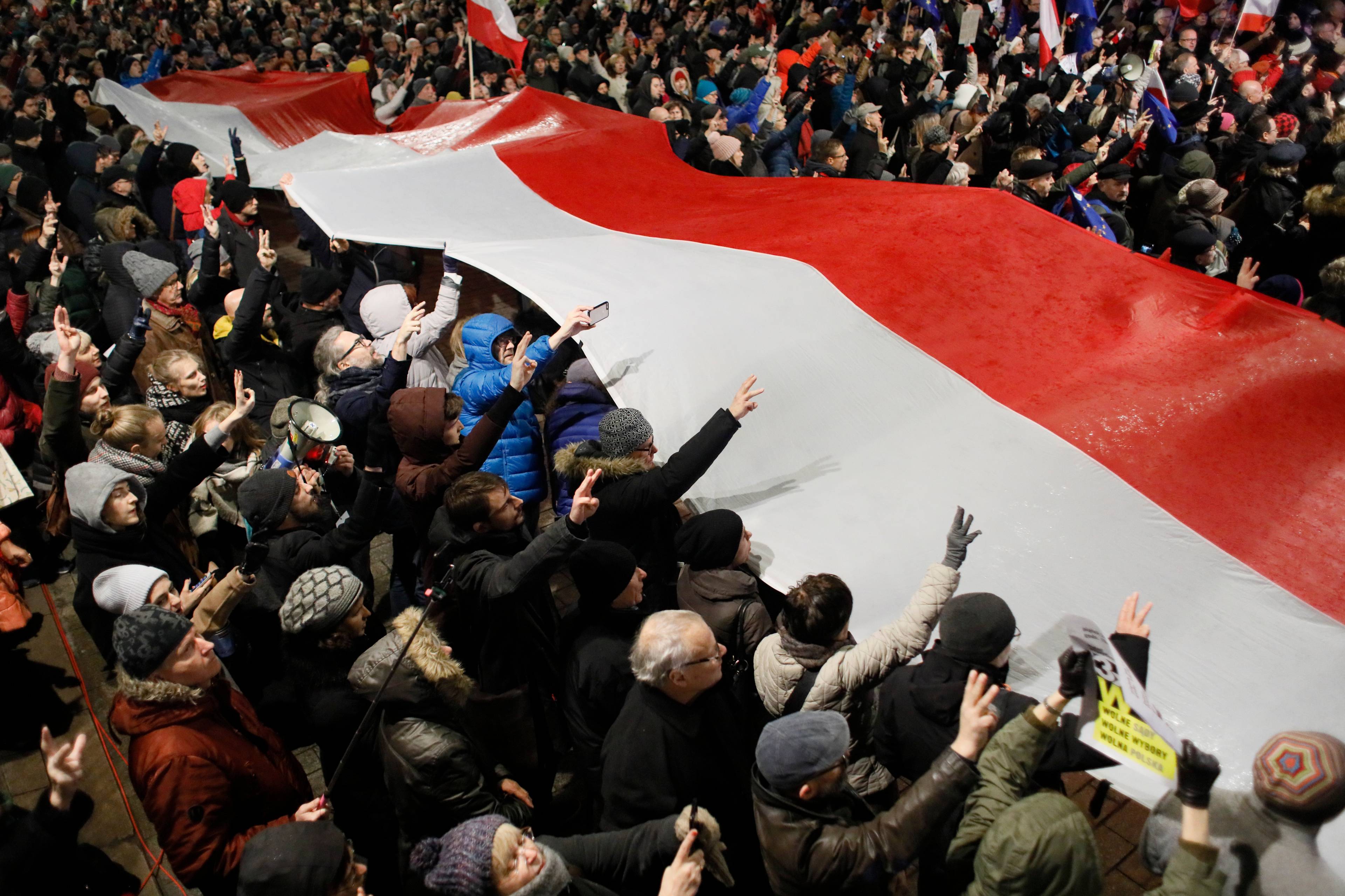 Demonstracja na ulicy. Protestujący trzymaja wielką flagę Polski