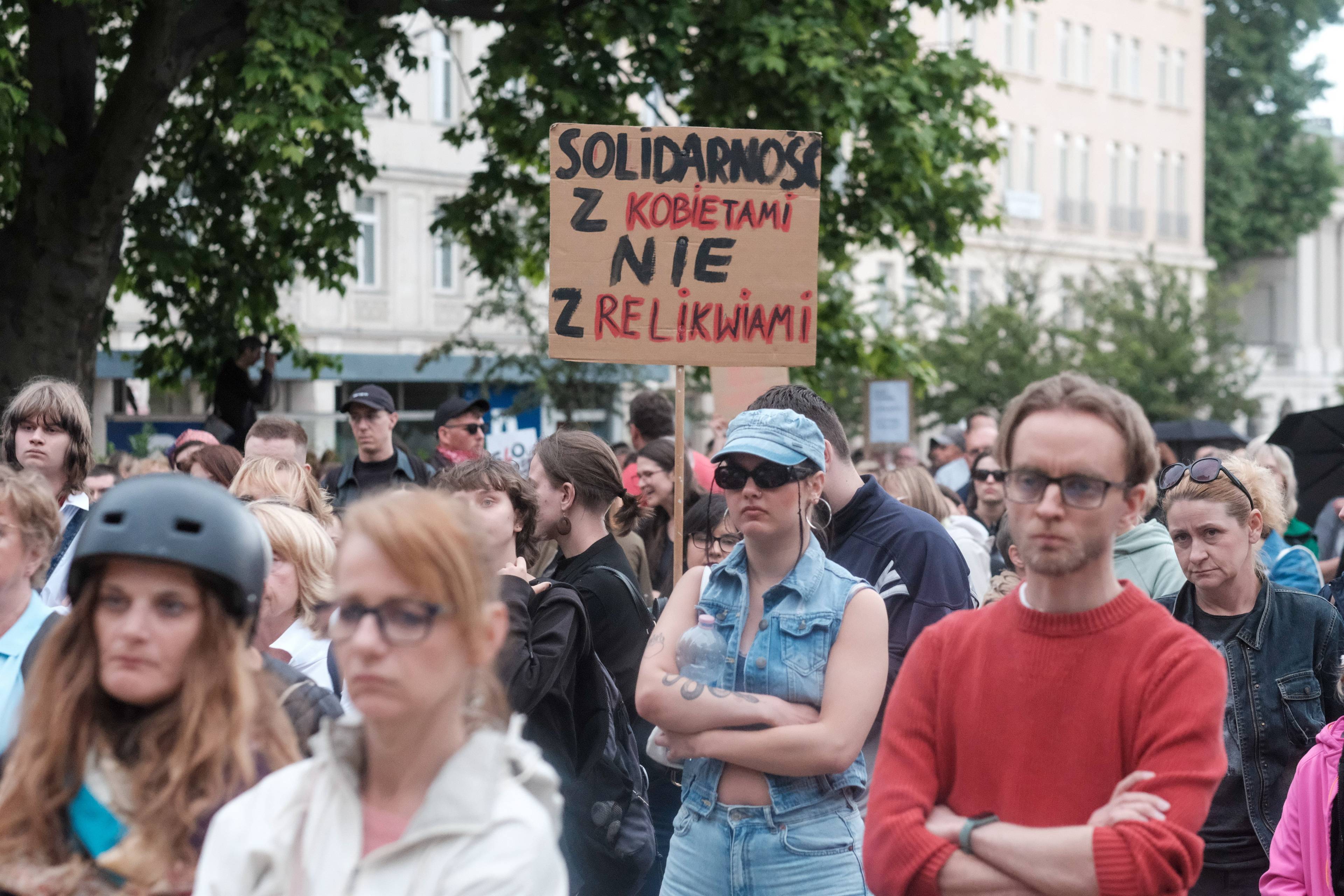 KObiety i męzczyxni stoją pod transparentem "Solidarność z kobietami, nie z relikwiami"