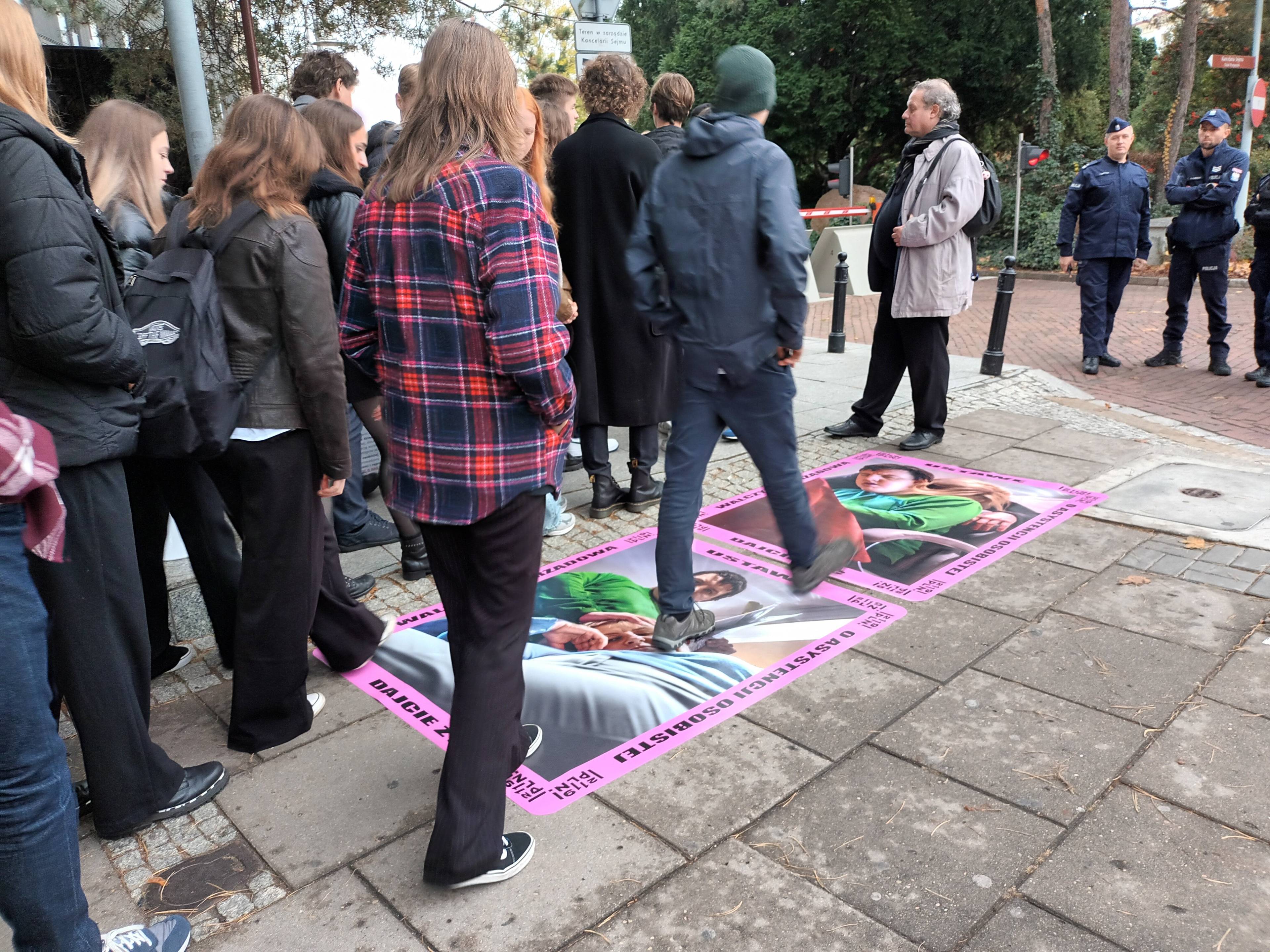 Młodzi ludzie przechodzą po plakatach na chodniku