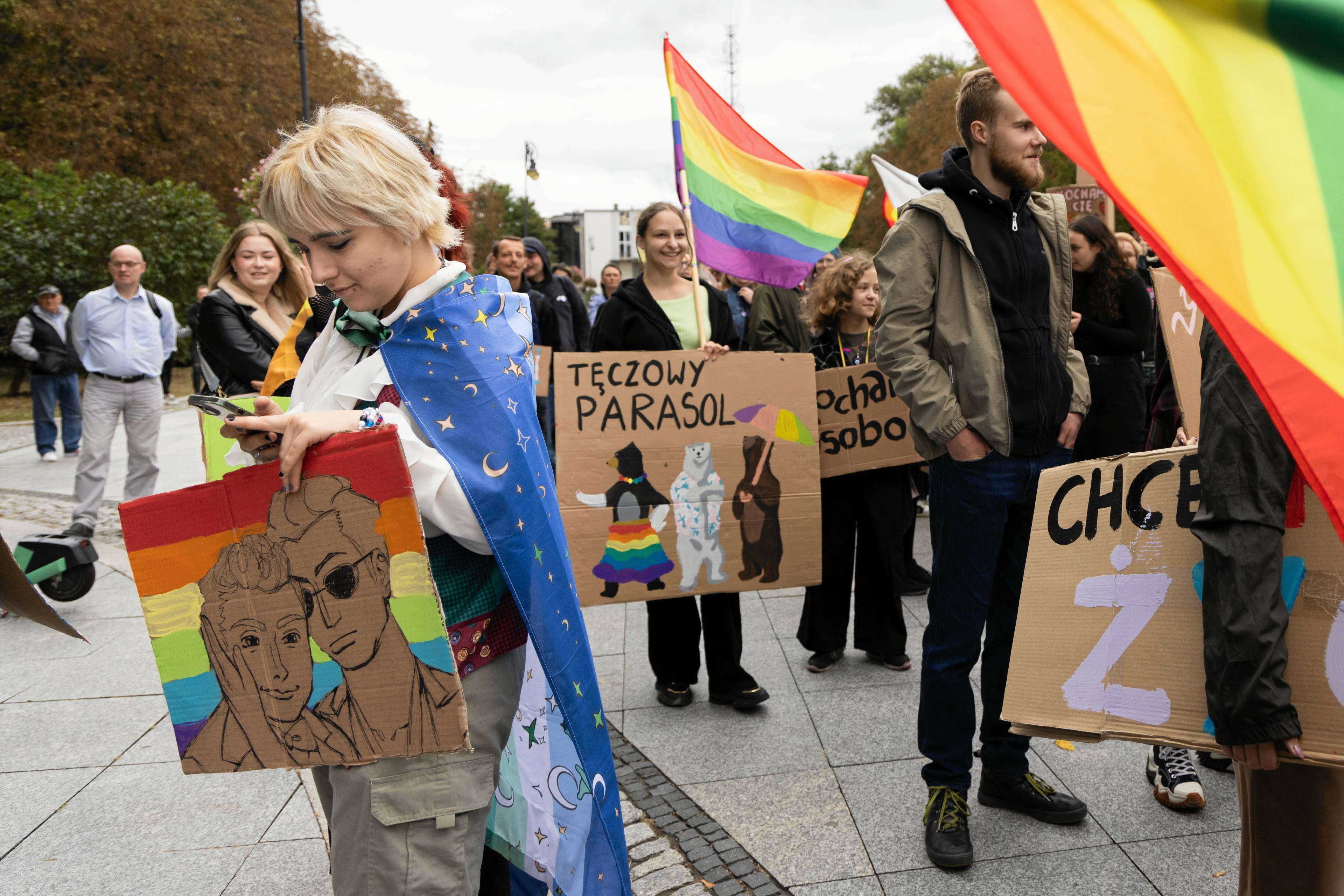 Młode osoby maszerujące pod tęczową flagą