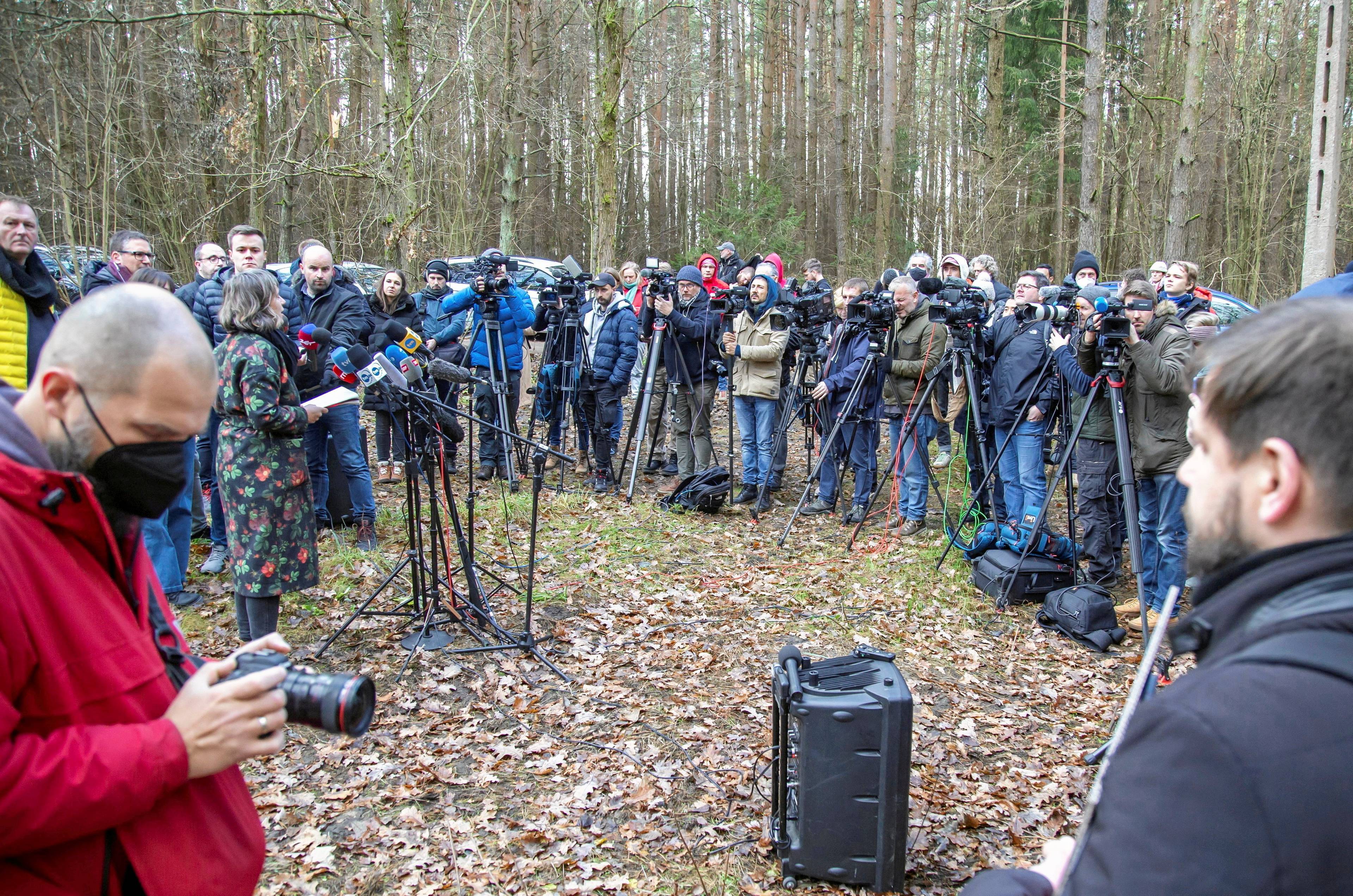 Grupa dziennikarzy z mikrofonami w lesie patrzy na aktywistów