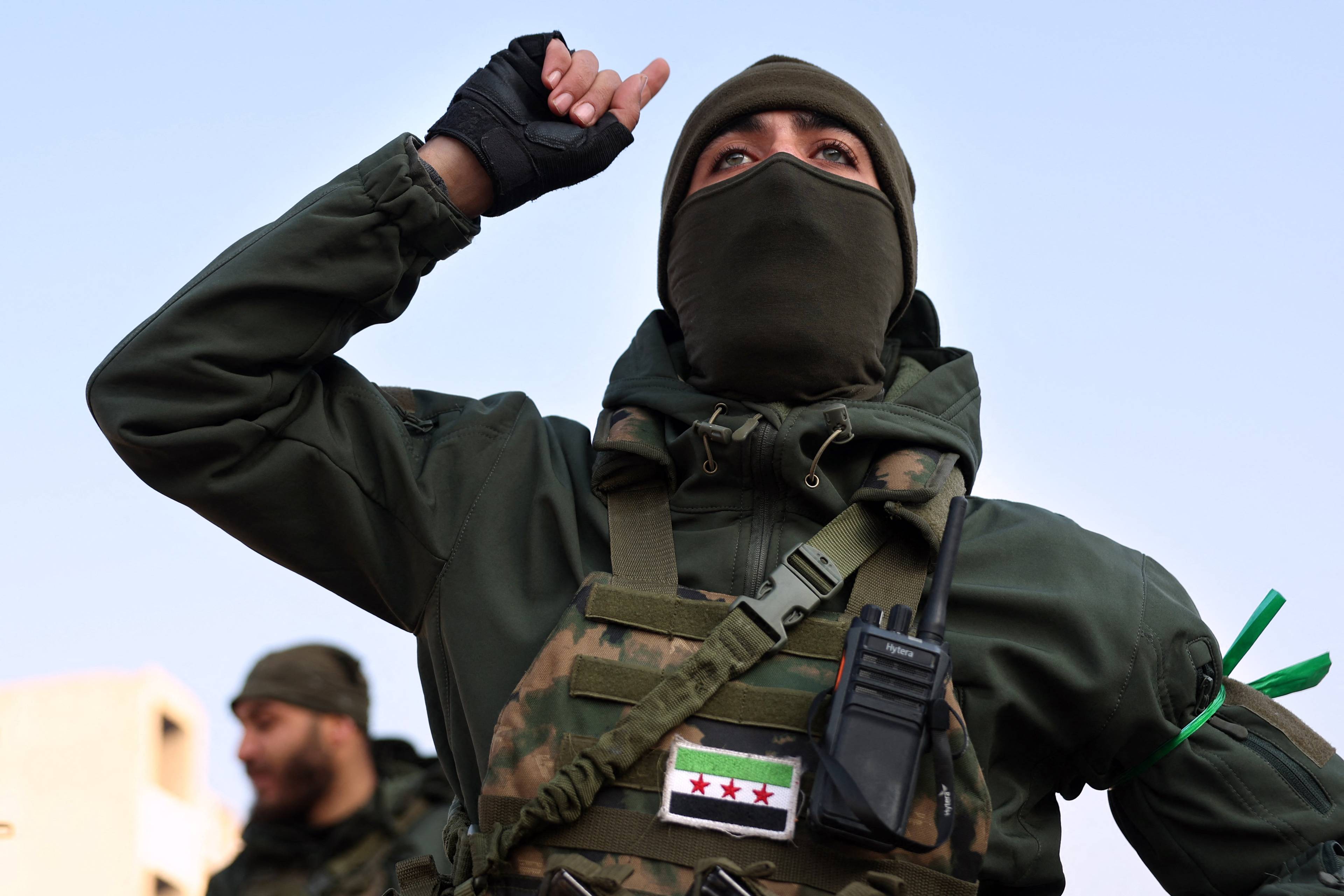 An anti-government fighter gestures in the city of Hama after forces captured the central Syrian city, on December 6, 2024. - Rebel forces pressing a lightning offensive in Syria aim to overthrow President Bashar al-Assad's rule, their Islamist leader said in an interview published on December 6. In little over a week, the offensive has seen Syria's second city Aleppo and strategically located Hama fall from Assad's control for the first time since the civil war began in 2011. (Photo by OMAR HAJ KADOUR / AFP)