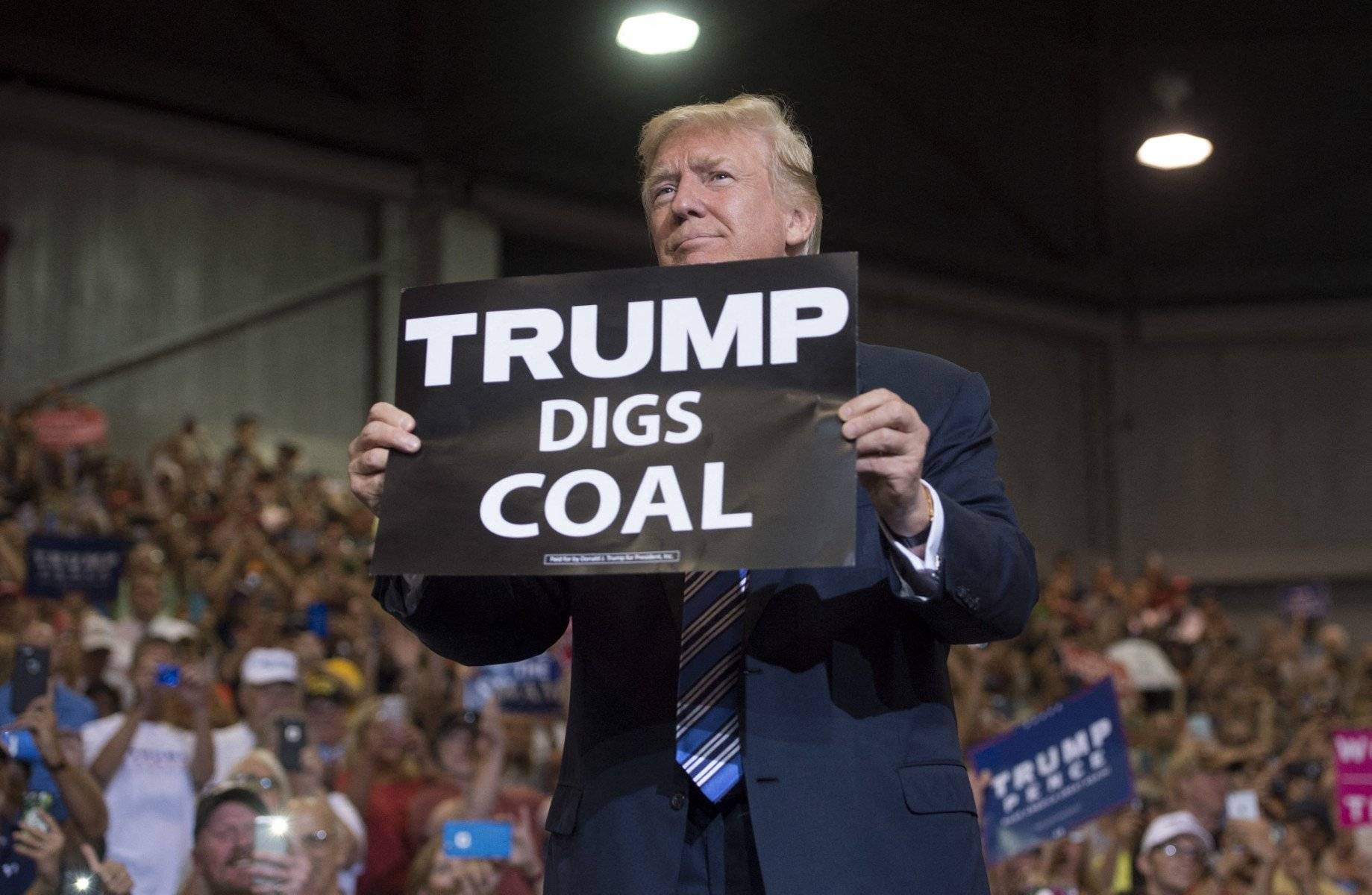 Donald Trump trzyma kartkę z napisem "Trump digs coal" (Trump wydobywa węgiel) podczas wiecu, w tle tłum jego zwolenników