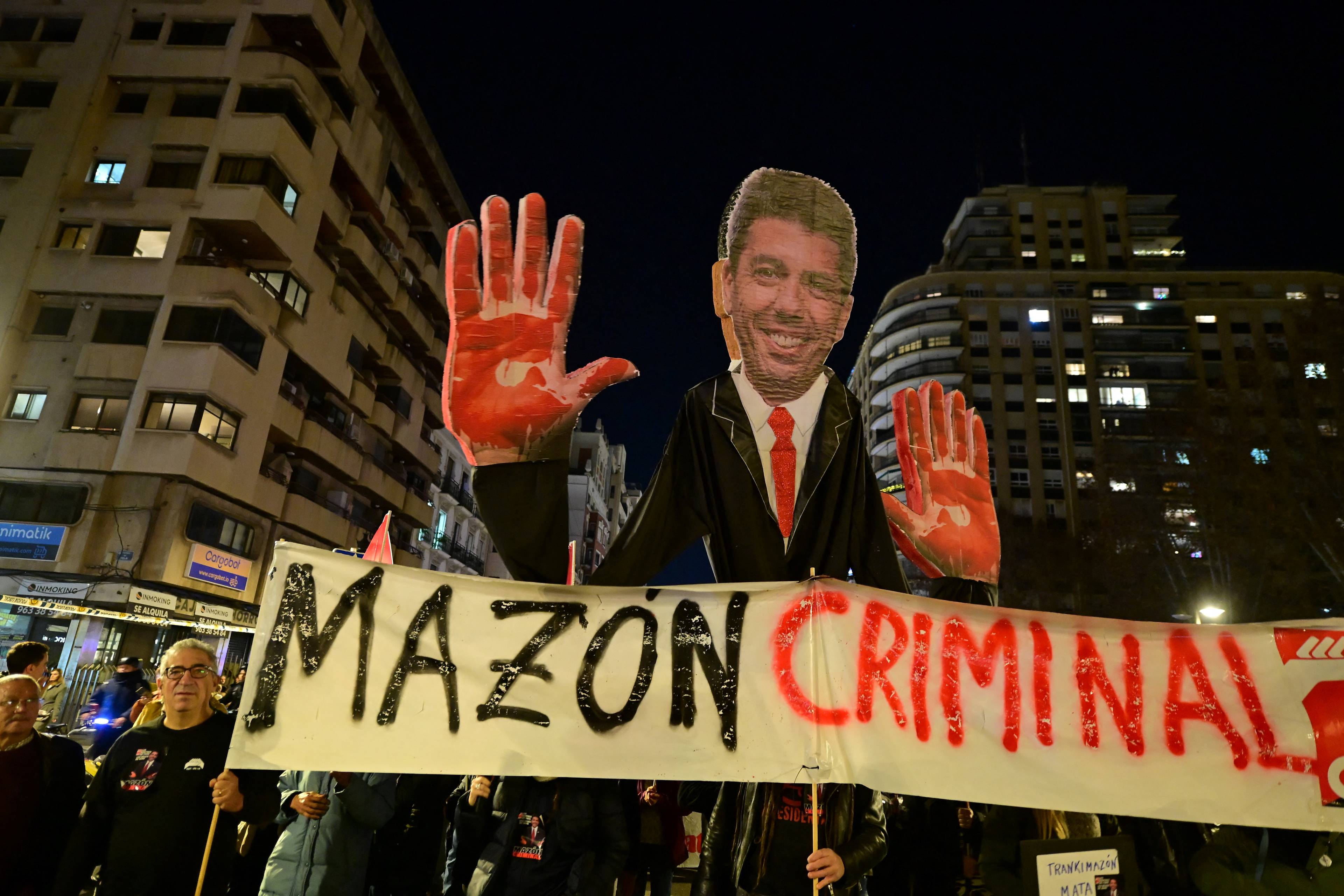 Demonstracja uliczna. Protestujący trzymają wielki wizerunek polityka i baner z napisem "Mazon criminal"