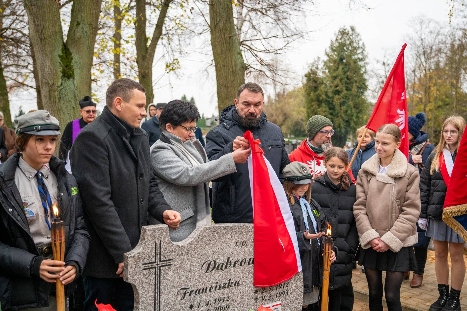 Grupa ludzi przy grobie z nazwiskiem Dąbrowicz