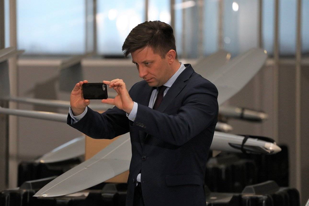 Michał Dworczyk fotofrafujący się na tle bojowego drona
