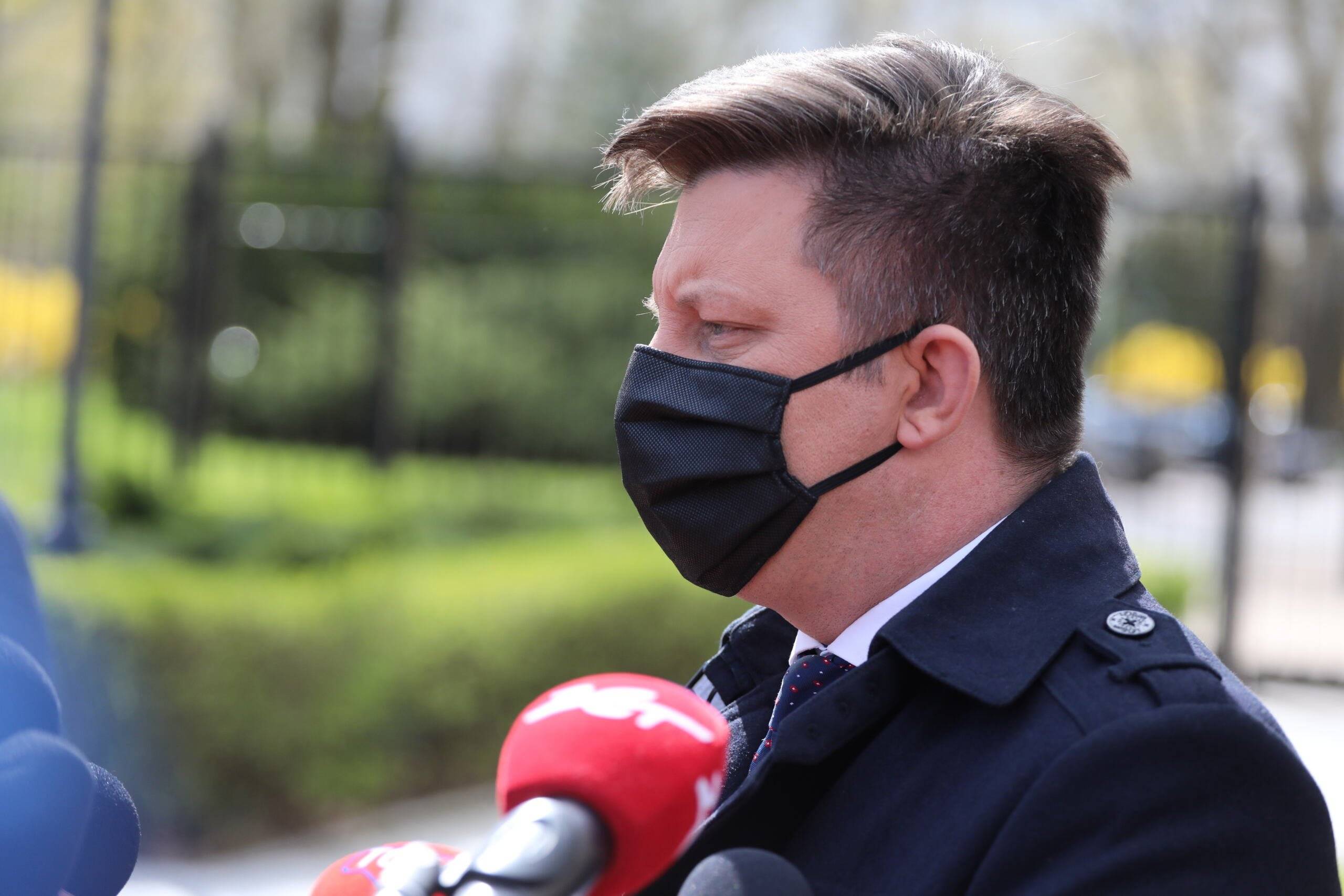 Michał Dworczyk w maseczce rozmawia z dziennikarzami przed budynkiem KPRM