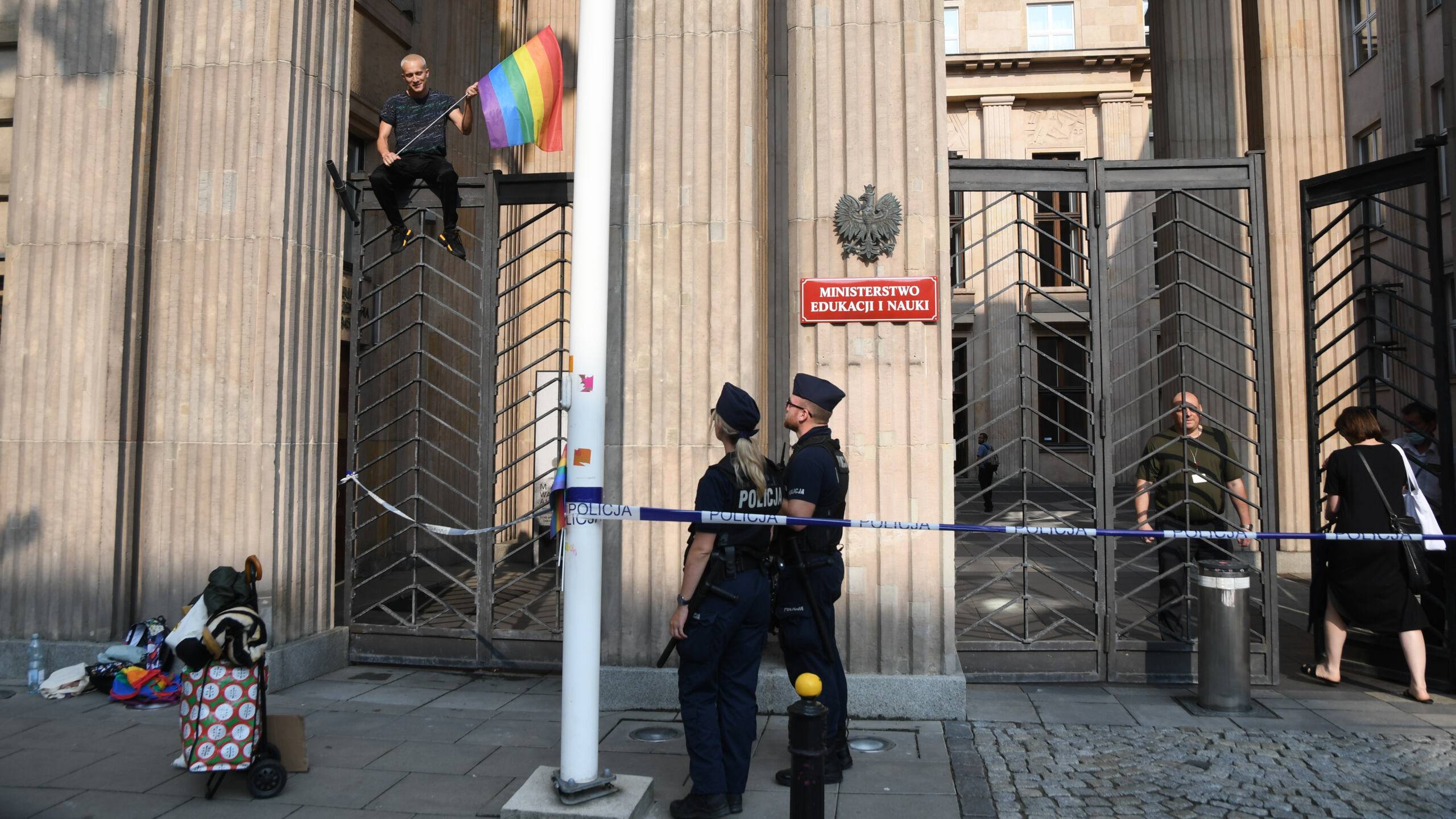 Osoba z tęczową flagą na bramie MEiN