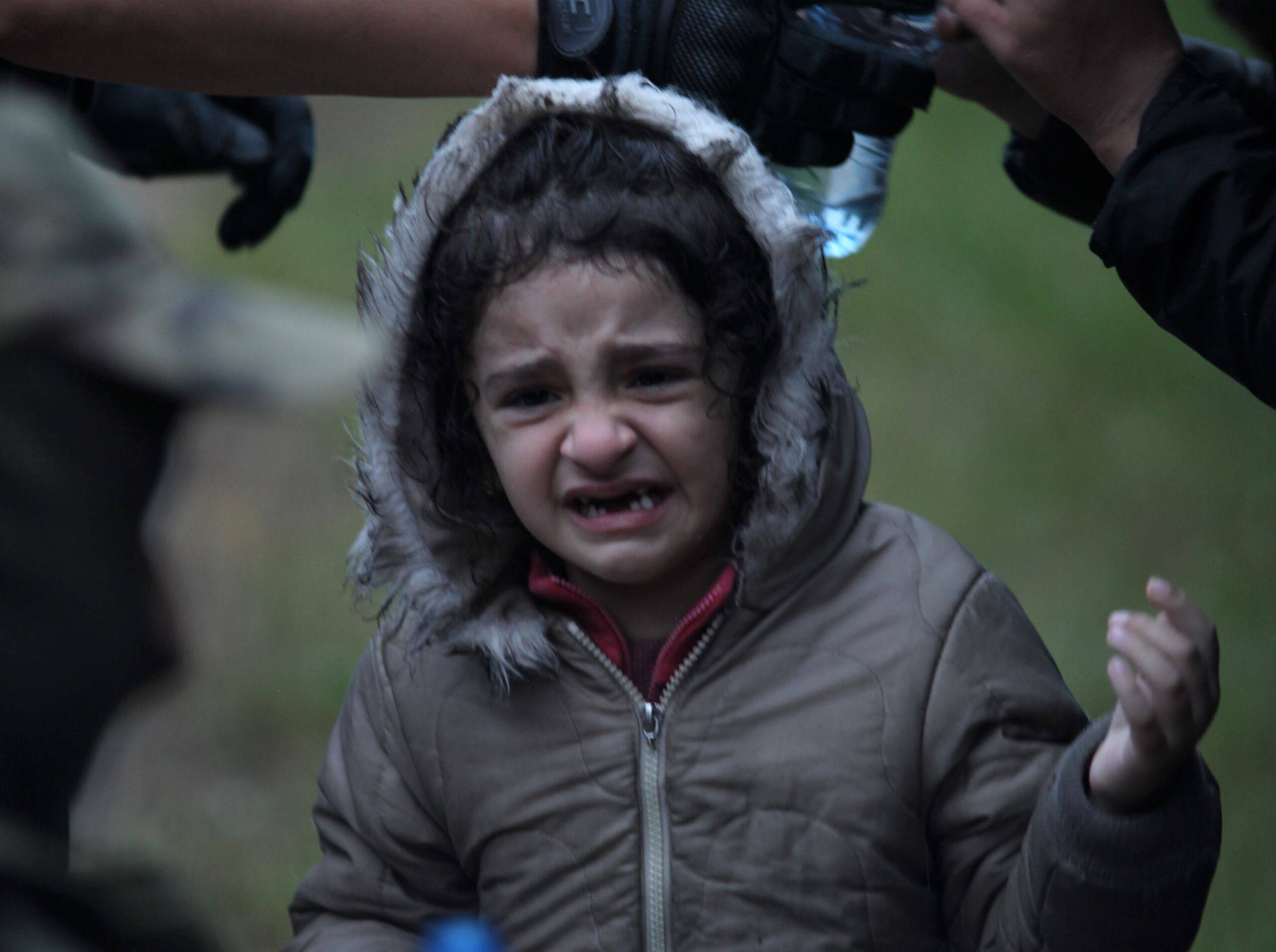 Płaczące dziecko w kurteczce z kapturem w lesie na granicy polsko-białoruskiej