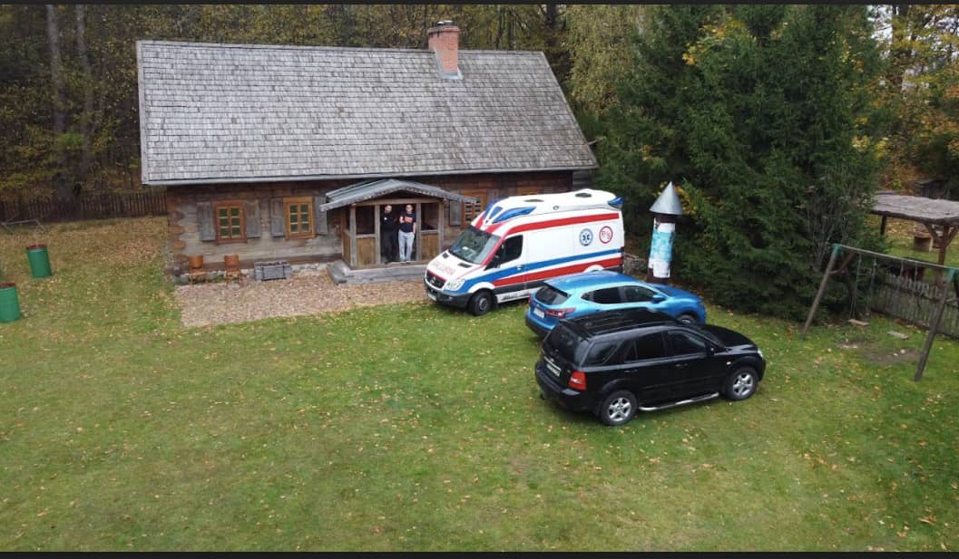 Dom w Puszczy - przed domem karetka i dwa samochody