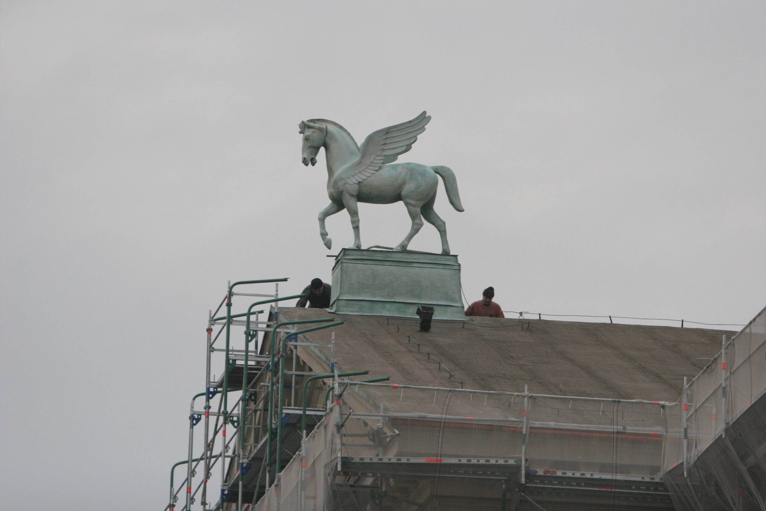 Skrzydlaty koń na remontowanym dachu budynku