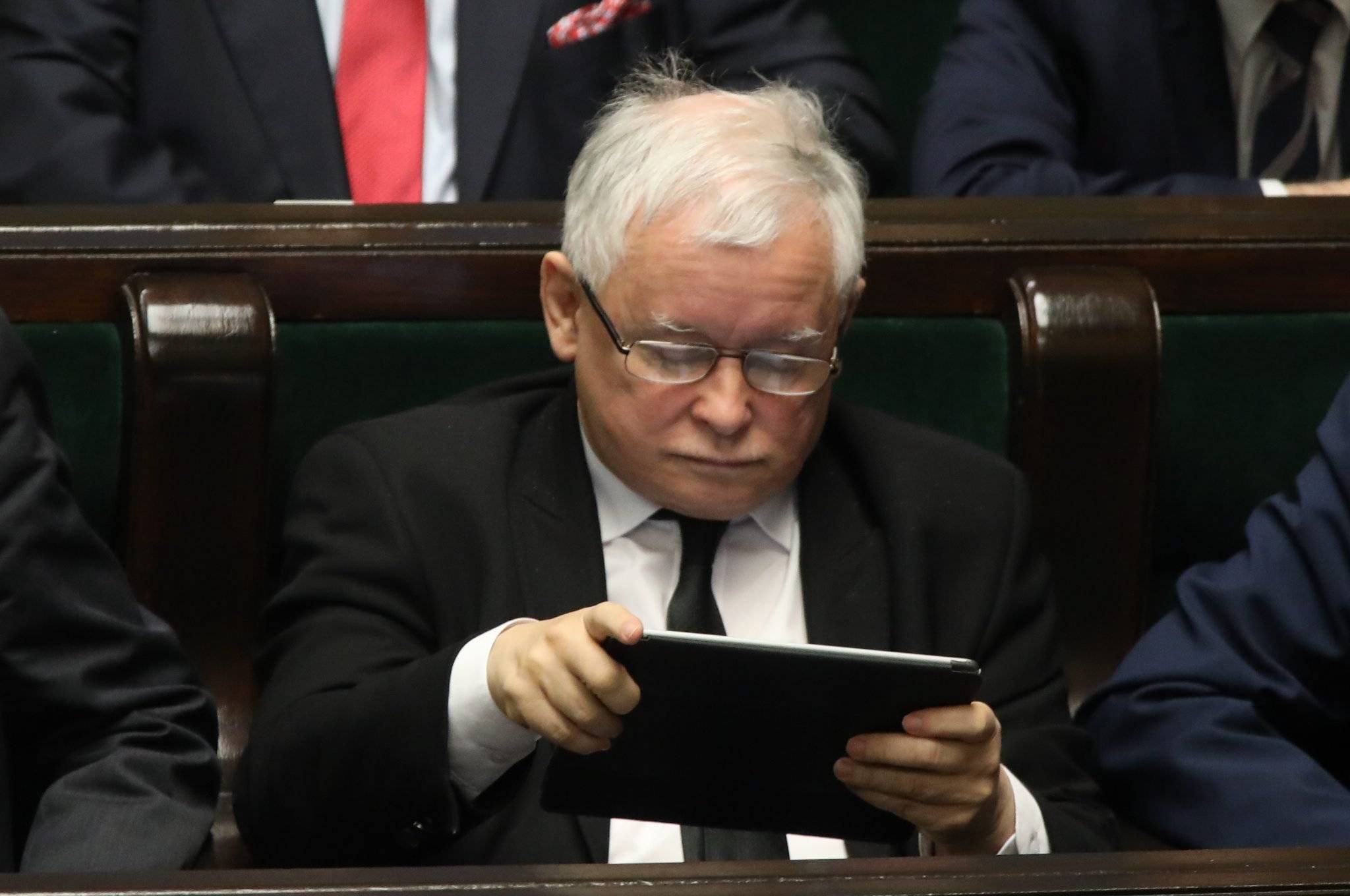 Jarosław Kaczyński czyta coś na tablecie w ławach sejmowych