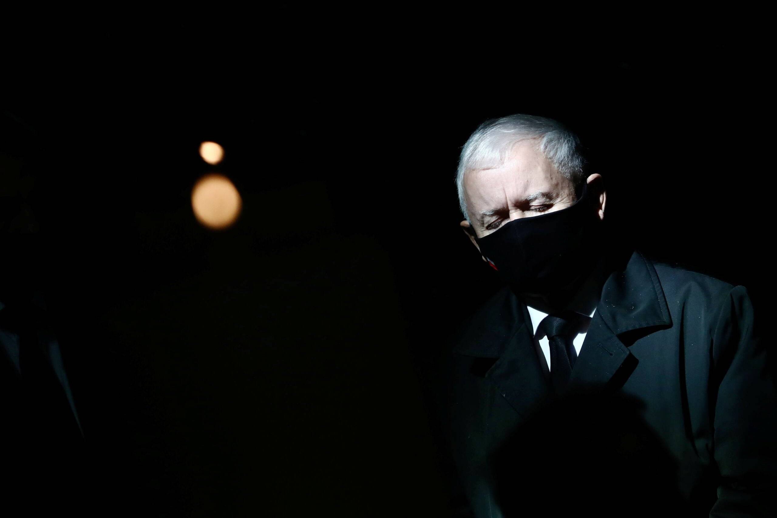 Jarosław Kaczyńsi w czarnej maseczce, stoi z zamkniętymi oczami, wokół ciemność
