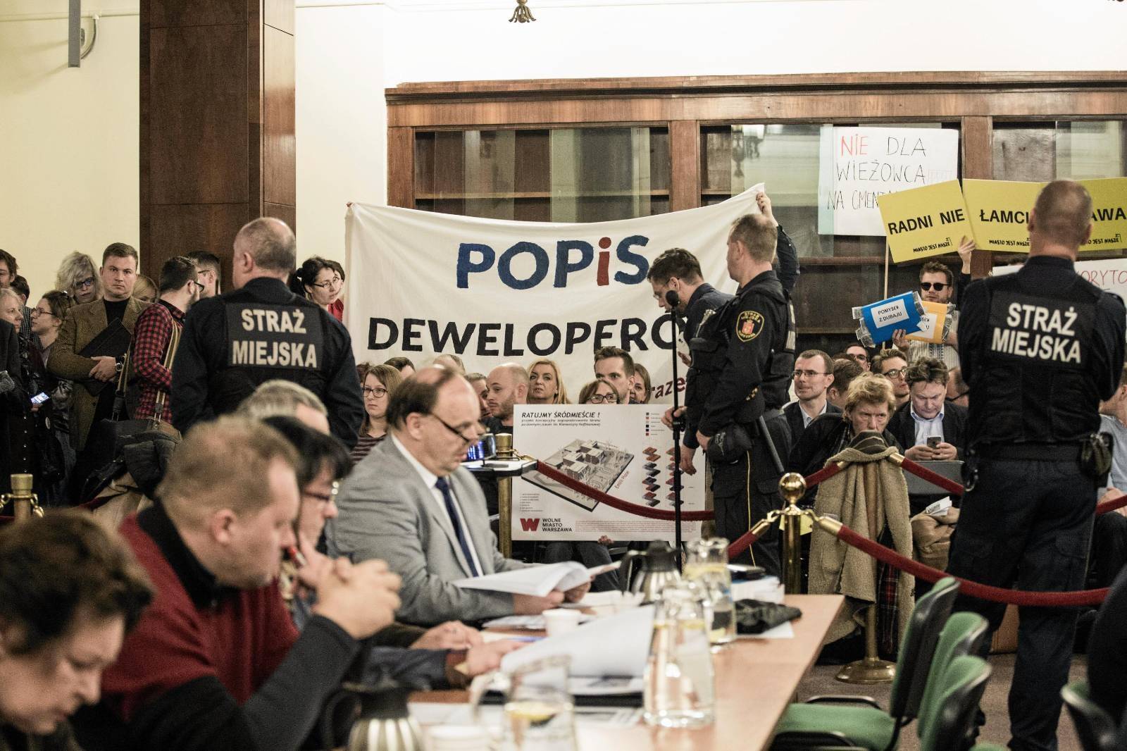 Protestujący z transparentem "POPiS deweloperów" na sesji rady miasta